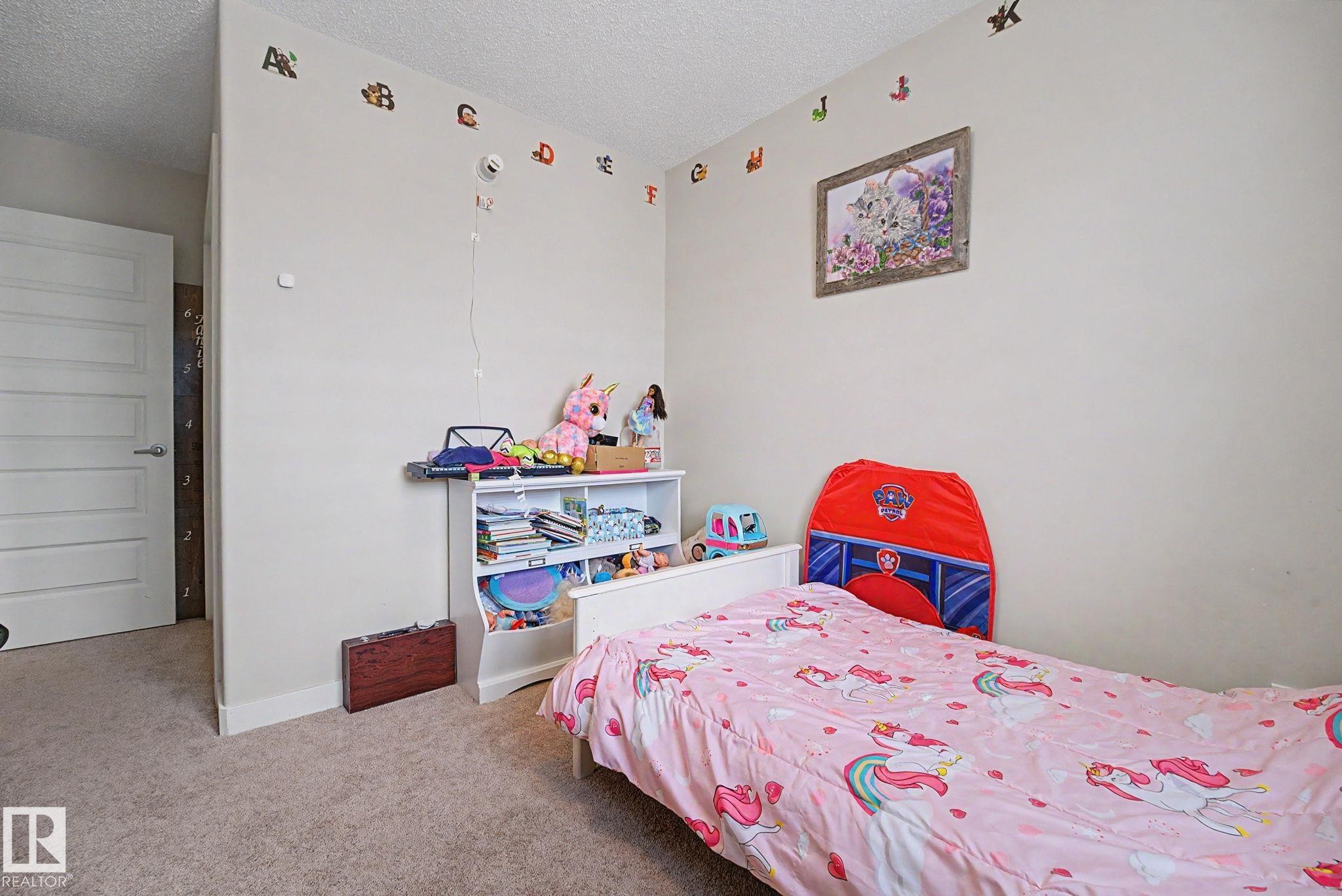 Neutral tone wall paint, textured ceiling, light-colored carpet flooring, white paneled door, and white trim - 3343 Weidle Way Sw, Edmonton, AB