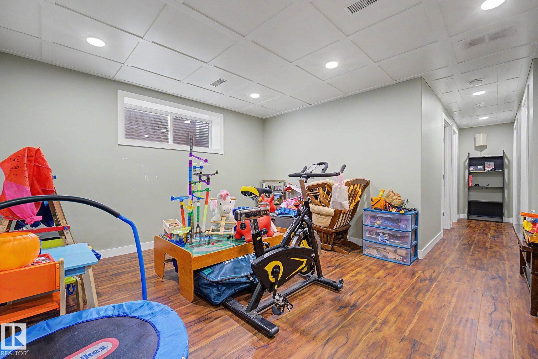 Room featuring wood-finish flooring, recessed lighting, and a drop ceiling with square paneling - 3343 Weidle Way Sw, Edmonton, AB