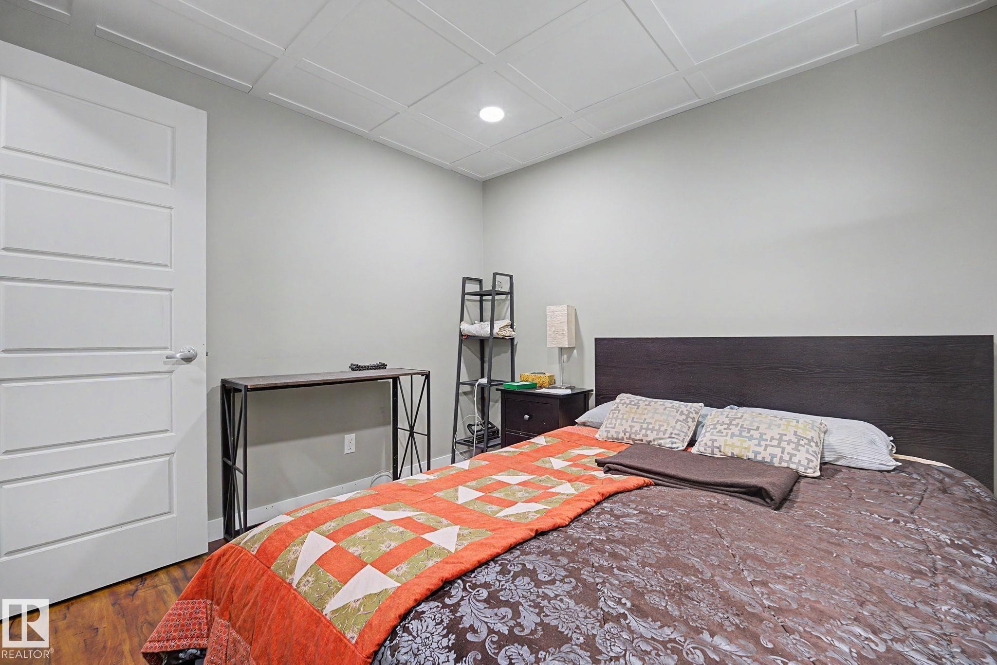 Wood-finish flooring, paneled interior door, recessed ceiling lighting, light gray wall paint, and tray ceiling detail - 3343 Weidle Way Sw, Edmonton, AB
