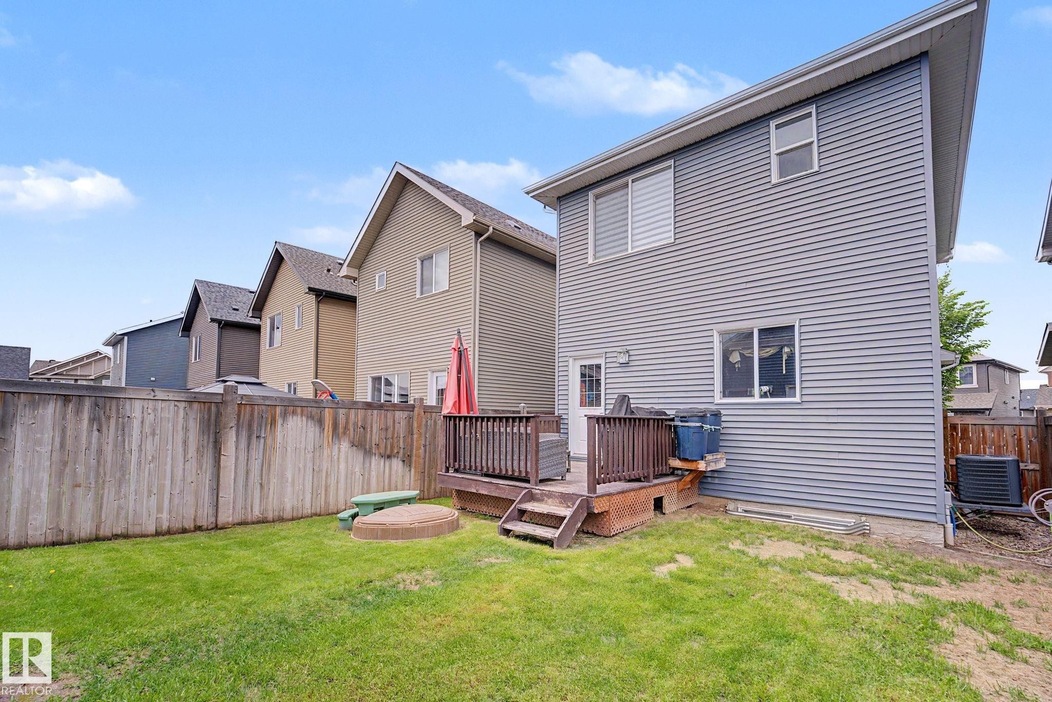 Expansive backyard featuring a manicured lawn, wood fencing, and a built-in wooden deck - 3343 Weidle Way Sw, Edmonton, AB