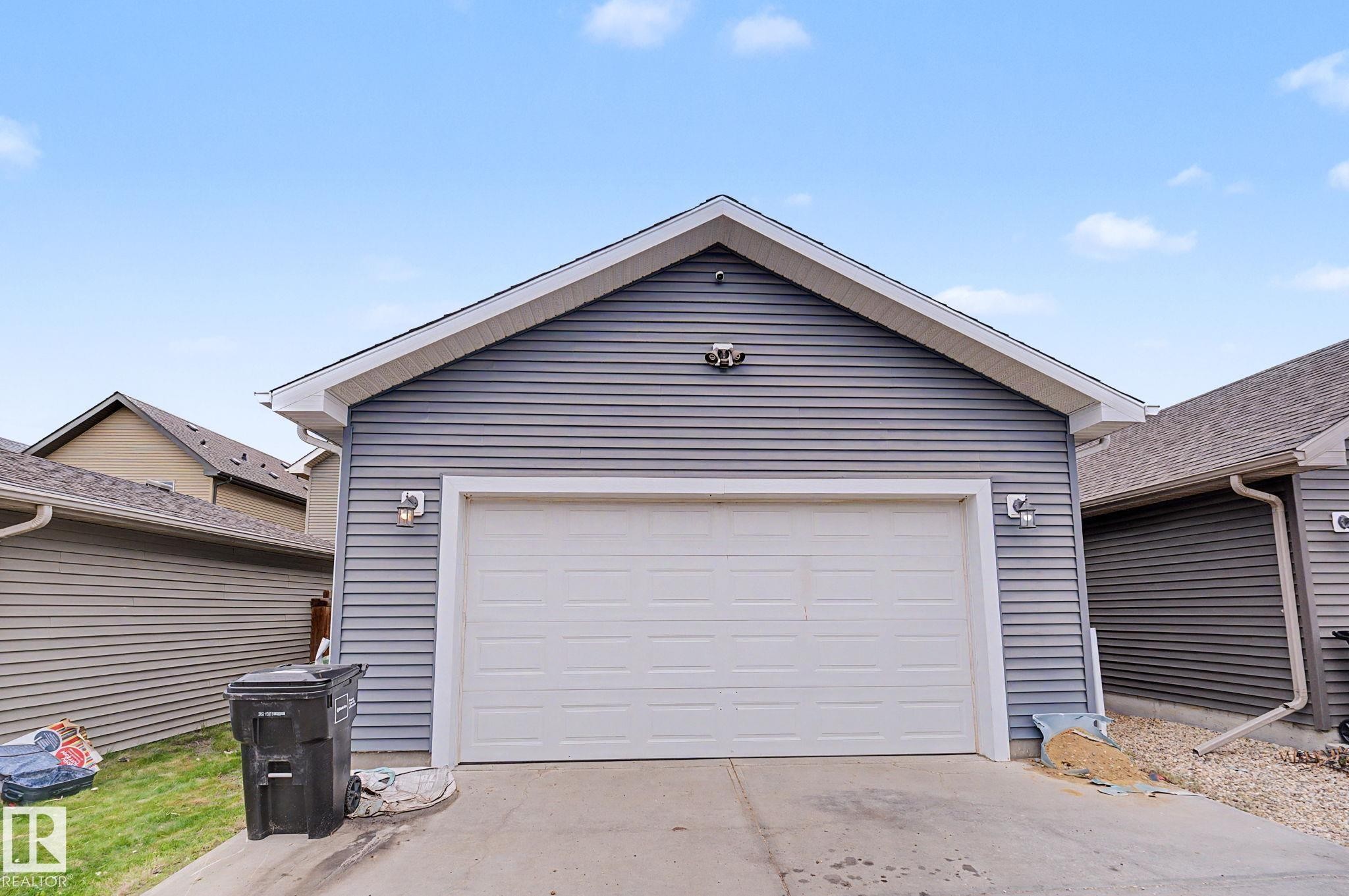 Detached garage featuring horizontal siding, a pitched roofline, and a white overhead door - 3343 Weidle Way Sw, Edmonton, AB