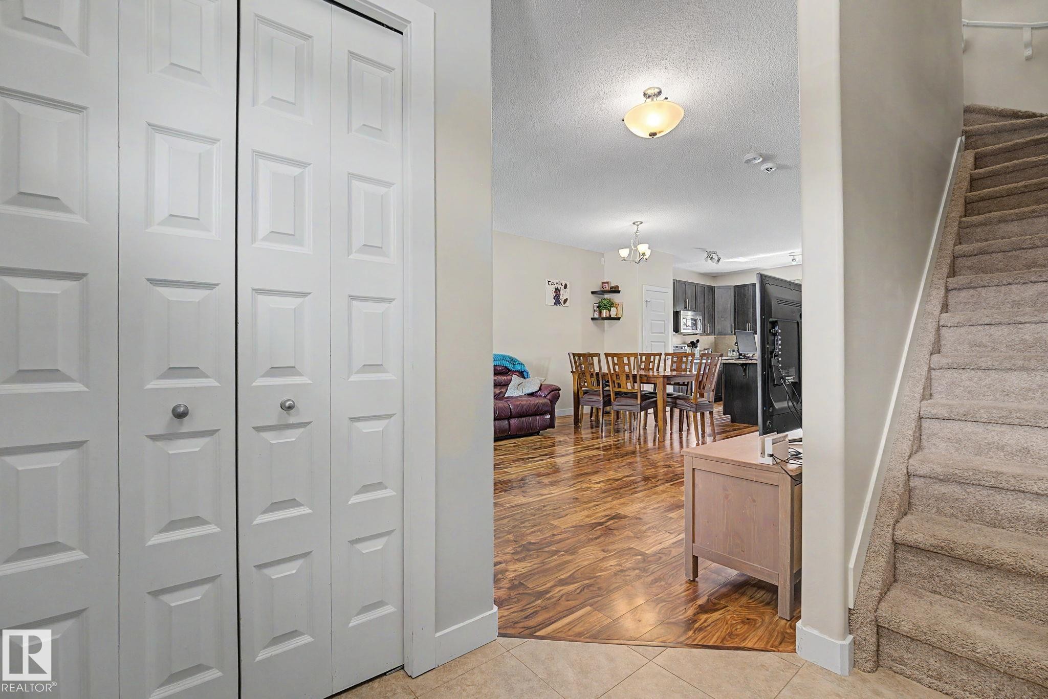 Entryway featuring bi-fold panel doors, tiled flooring, and a carpeted staircase - 3343 Weidle Way Sw, Edmonton, AB