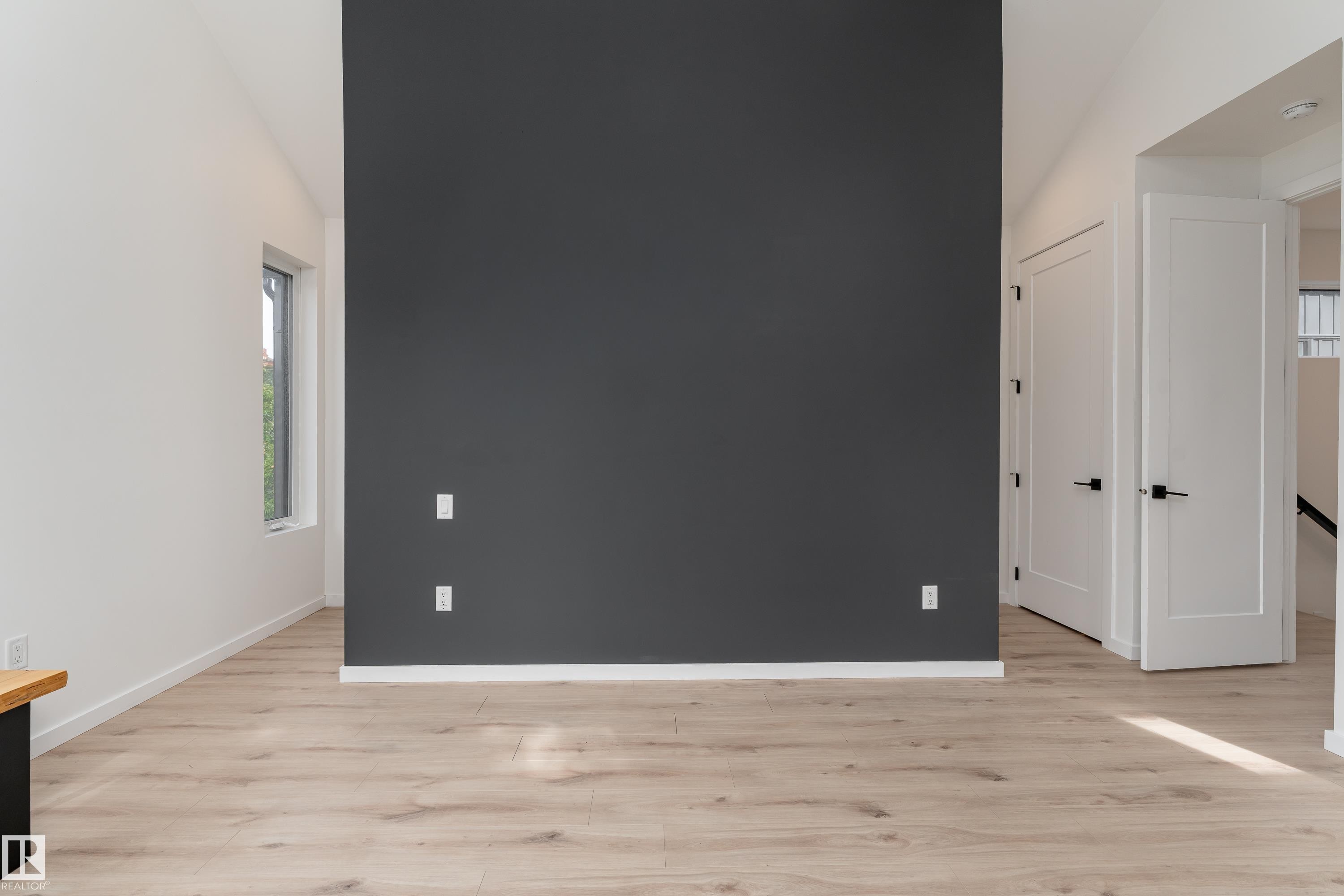 Vaulted ceiling, light wood-finish flooring, accent wall, modern interior doors, and a rectangular window - 10138 90 Street Nw, Edmonton, AB
