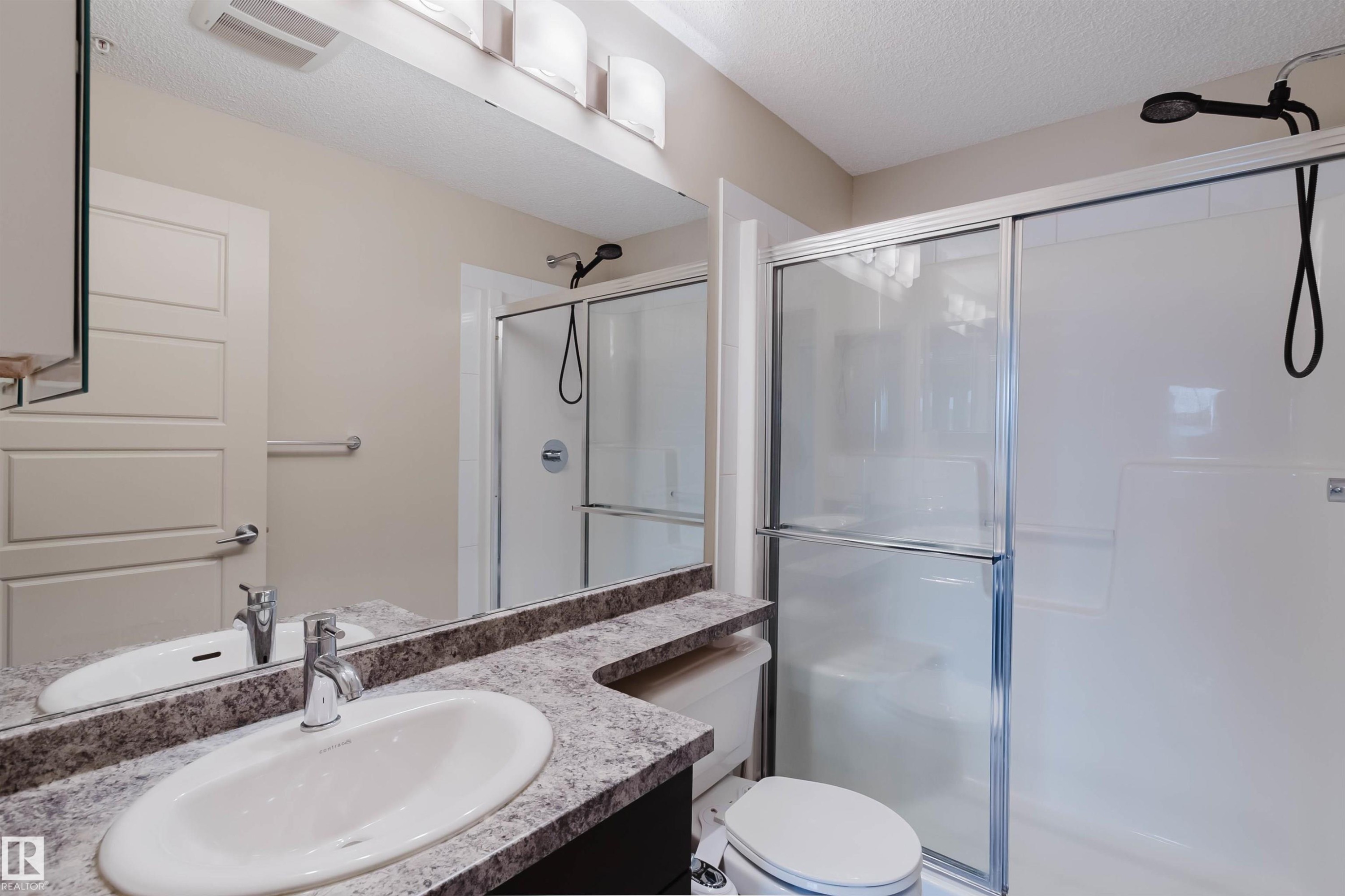Vanity with an oval undermount sink, chrome faucet, and speckled countertop - #304 6084 Stanton Dr Sw, Edmonton, AB - Indoor Photo Showing Bathroom
