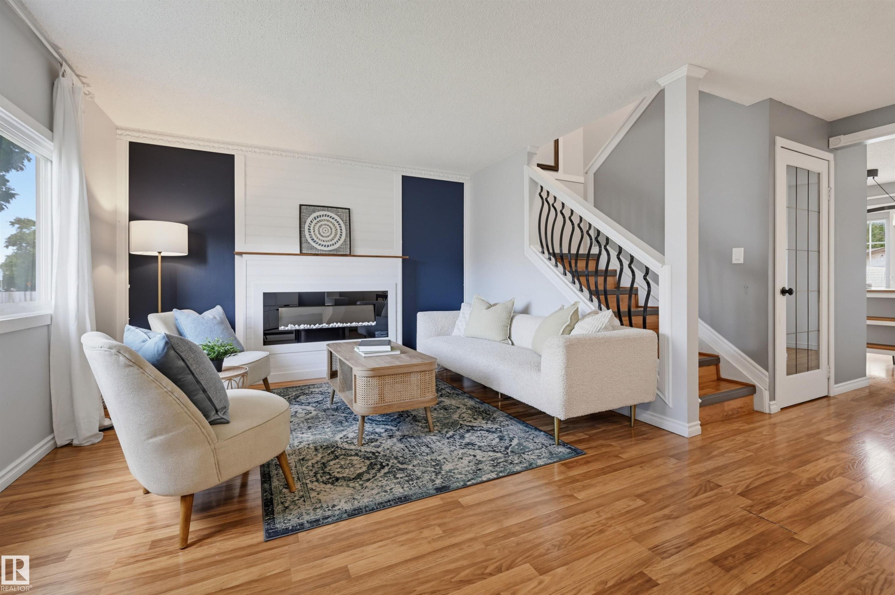 Wood-finish flooring, staircase with decorative wrought iron balusters, built-in fireplace, and white trim accents - 4125 38 Street Nw, Edmonton, AB