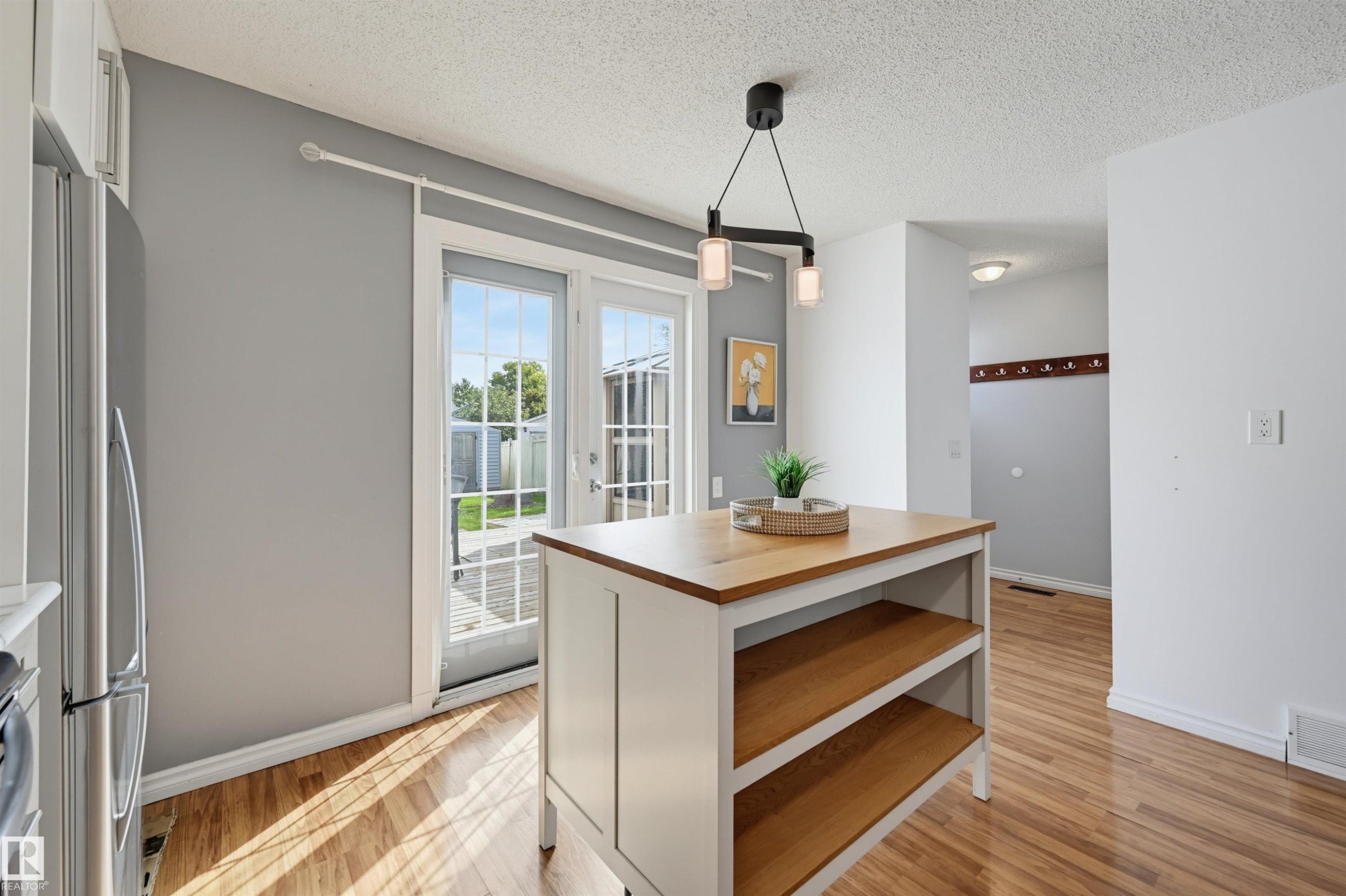 Kitchen island with wood-finish countertop, double French doors, and wood-finish flooring - 4125 38 Street Nw, Edmonton, AB