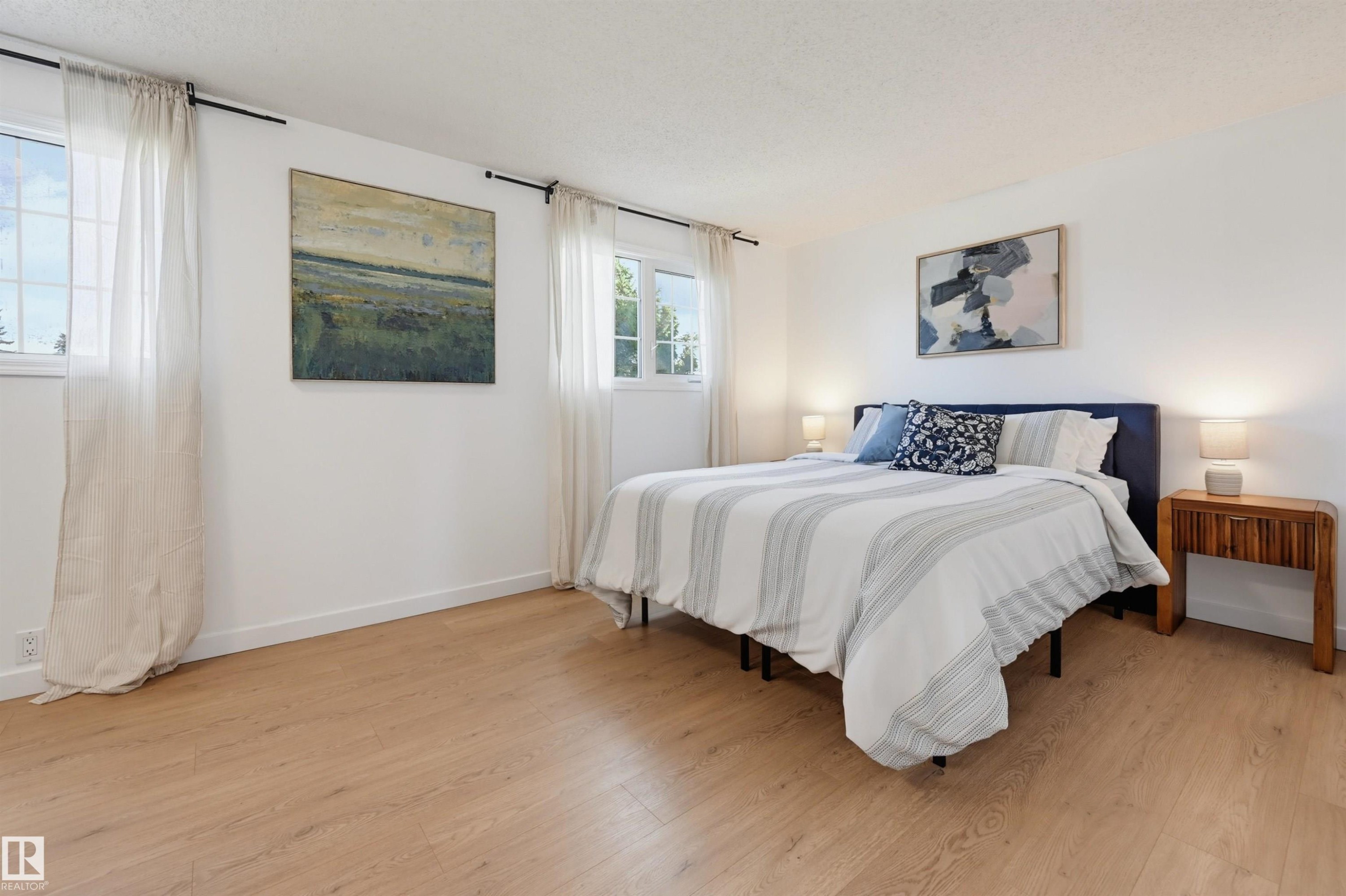 Wood-finish flooring, white walls, and multiple windows with curtain rods - 4125 38 Street Nw, Edmonton, AB