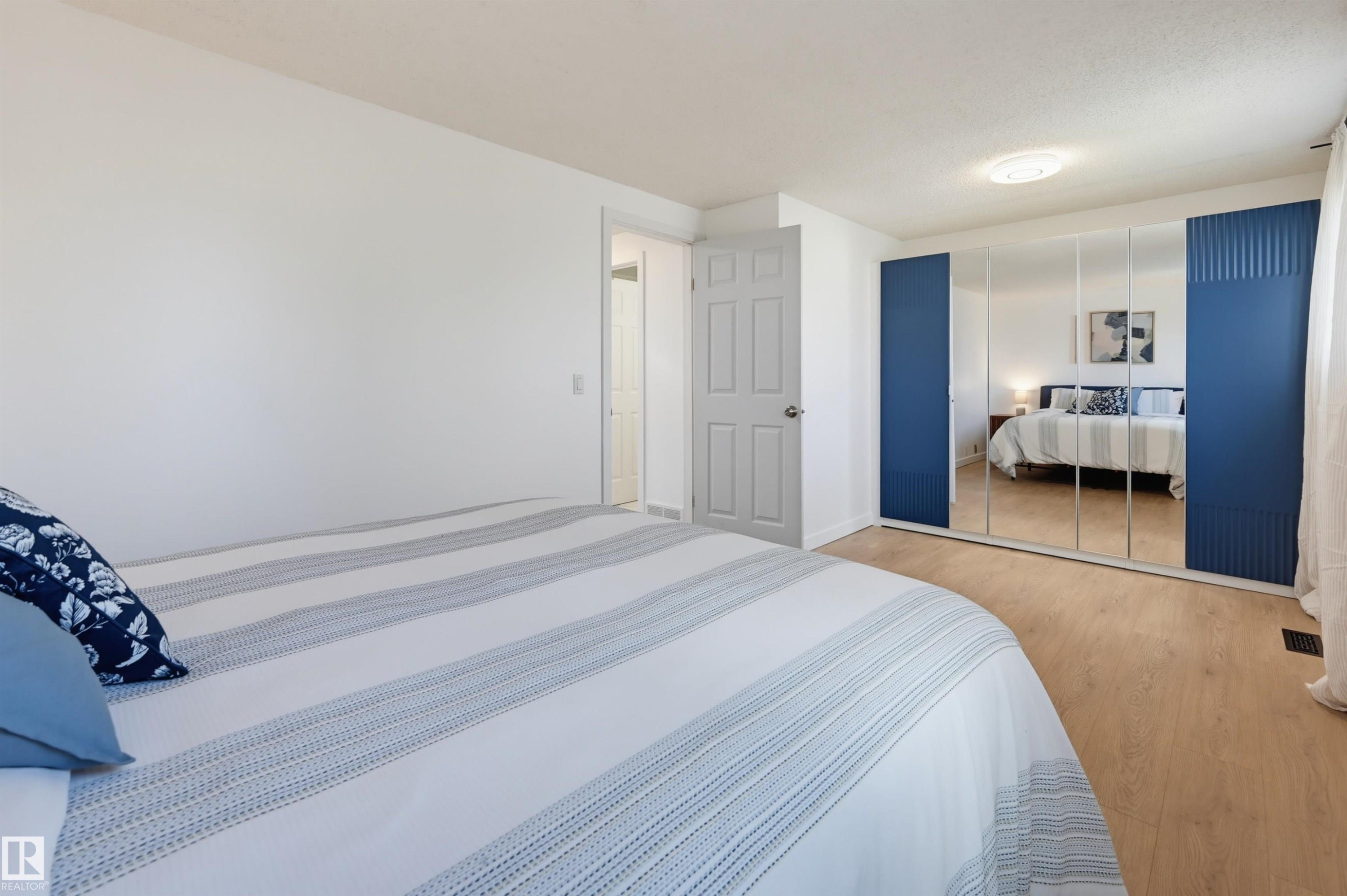 Wood-finish flooring throughout, white painted walls, and a white paneled door - 4125 38 Street Nw, Edmonton, AB