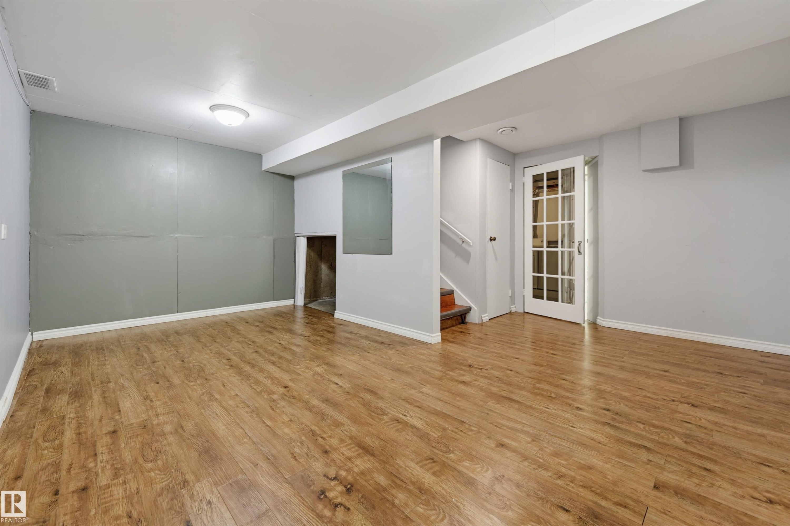 Wood-finish flooring throughout, white baseboards, and a glass-paneled door - 4125 38 Street Nw, Edmonton, AB