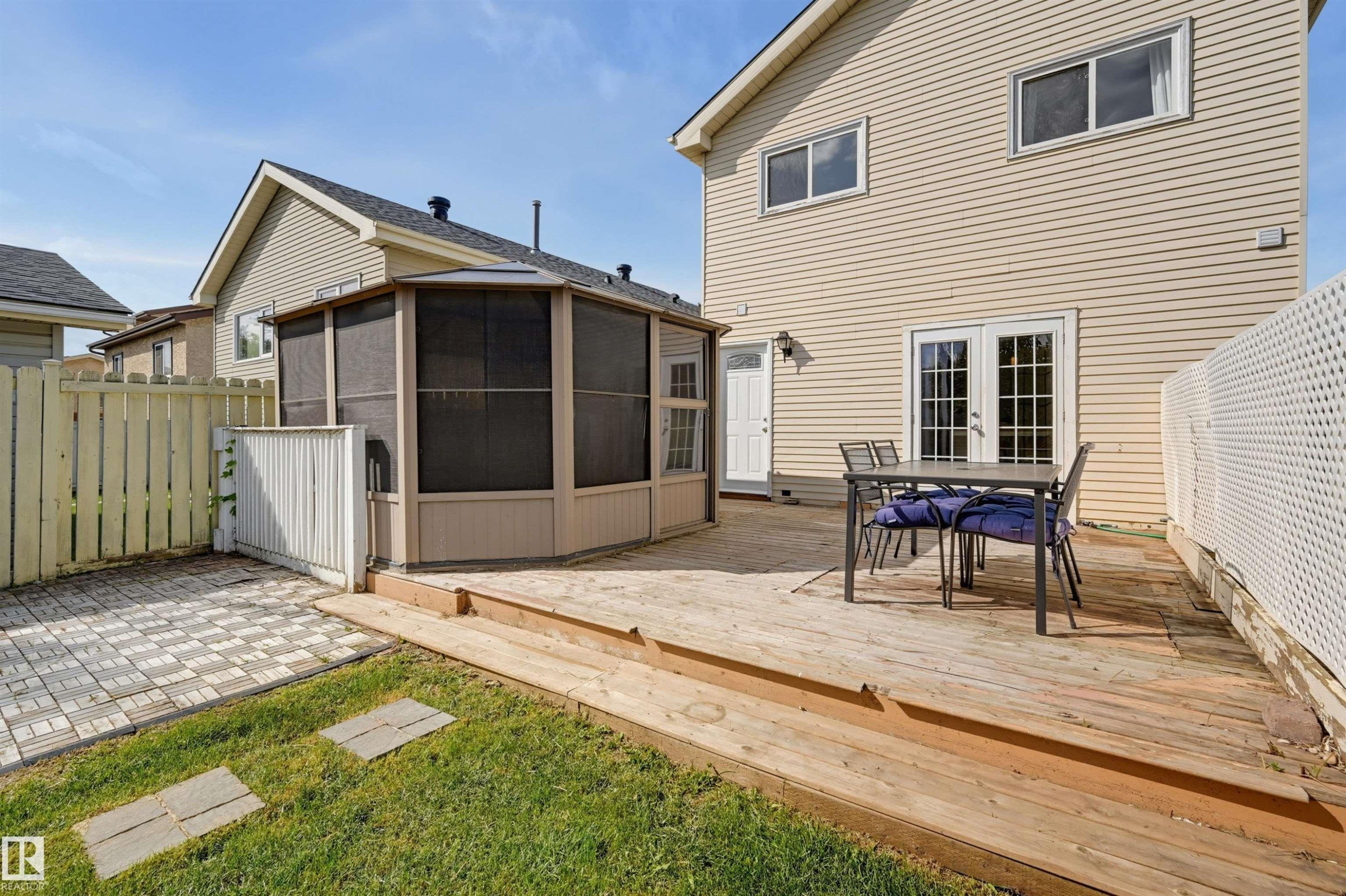 Expansive wood deck with dual French doors, a screened-in gazebo, and a paved patio area - 4125 38 Street Nw, Edmonton, AB