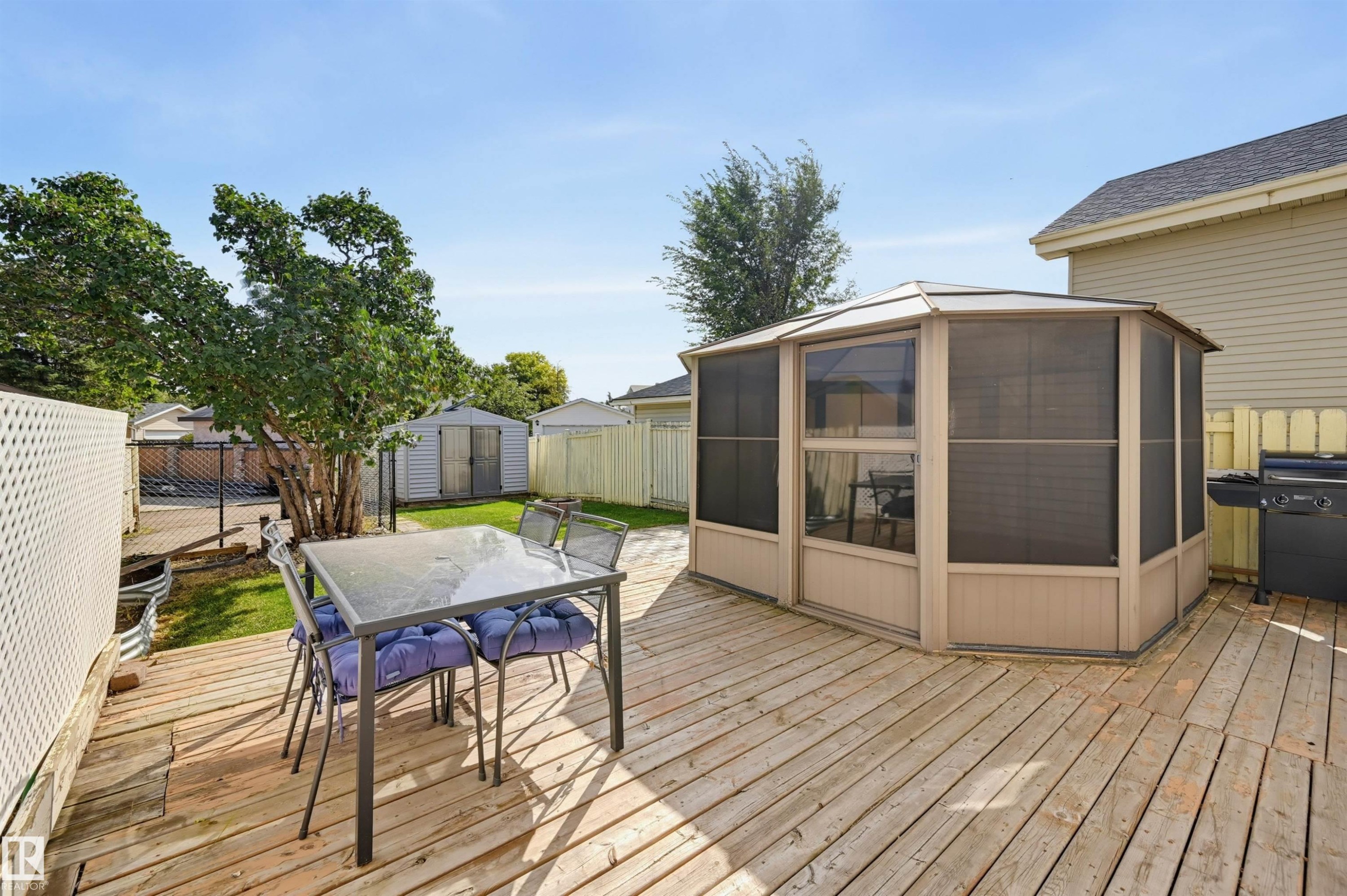 Expansive wood-finish deck featuring a screened gazebo, white lattice privacy wall, and green lawn - 4125 38 Street Nw, Edmonton, AB