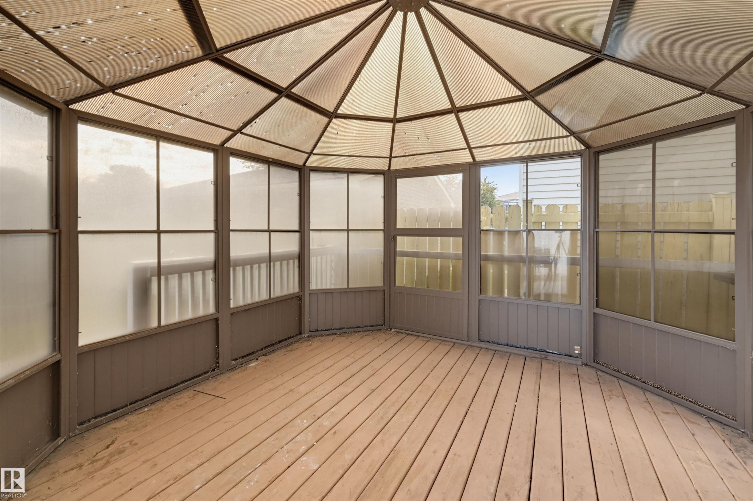 Gazebo structure with a multi-paneled translucent roof, frosted panel walls, wood-finish flooring, and a panel door - 4125 38 Street Nw, Edmonton, AB