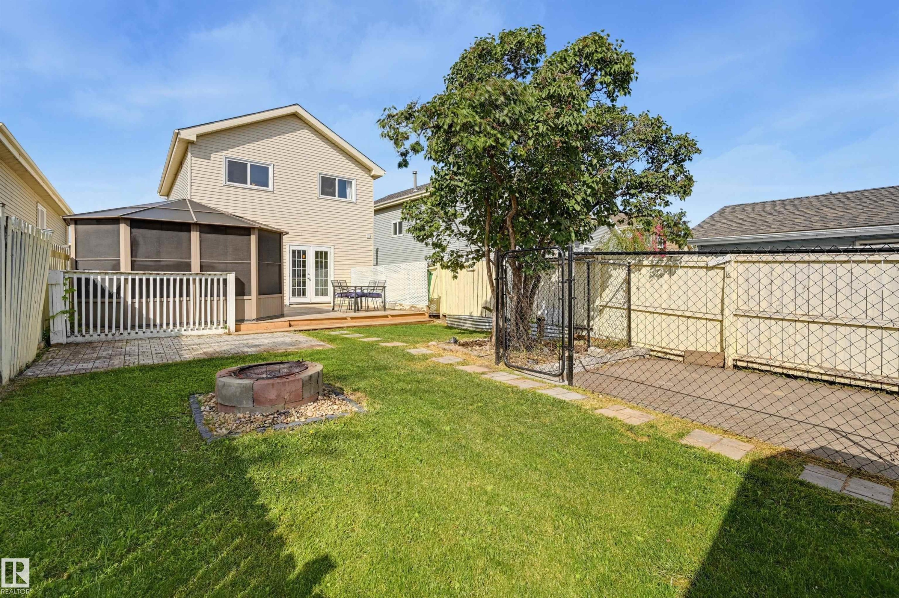 Expansive grassy yard featuring a built-in fire pit, a multi-level deck, and a screened gazebo structure - 4125 38 Street Nw, Edmonton, AB
