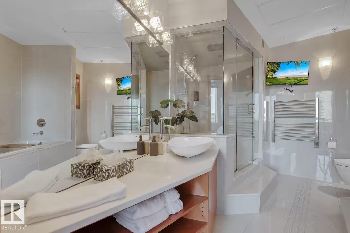 Dual vessel sinks, walk-in glass shower, built-in bathtub, wood-finish open shelving, and wall-mounted towel warmer - #701 10105 109 St Nw, Edmonton, AB