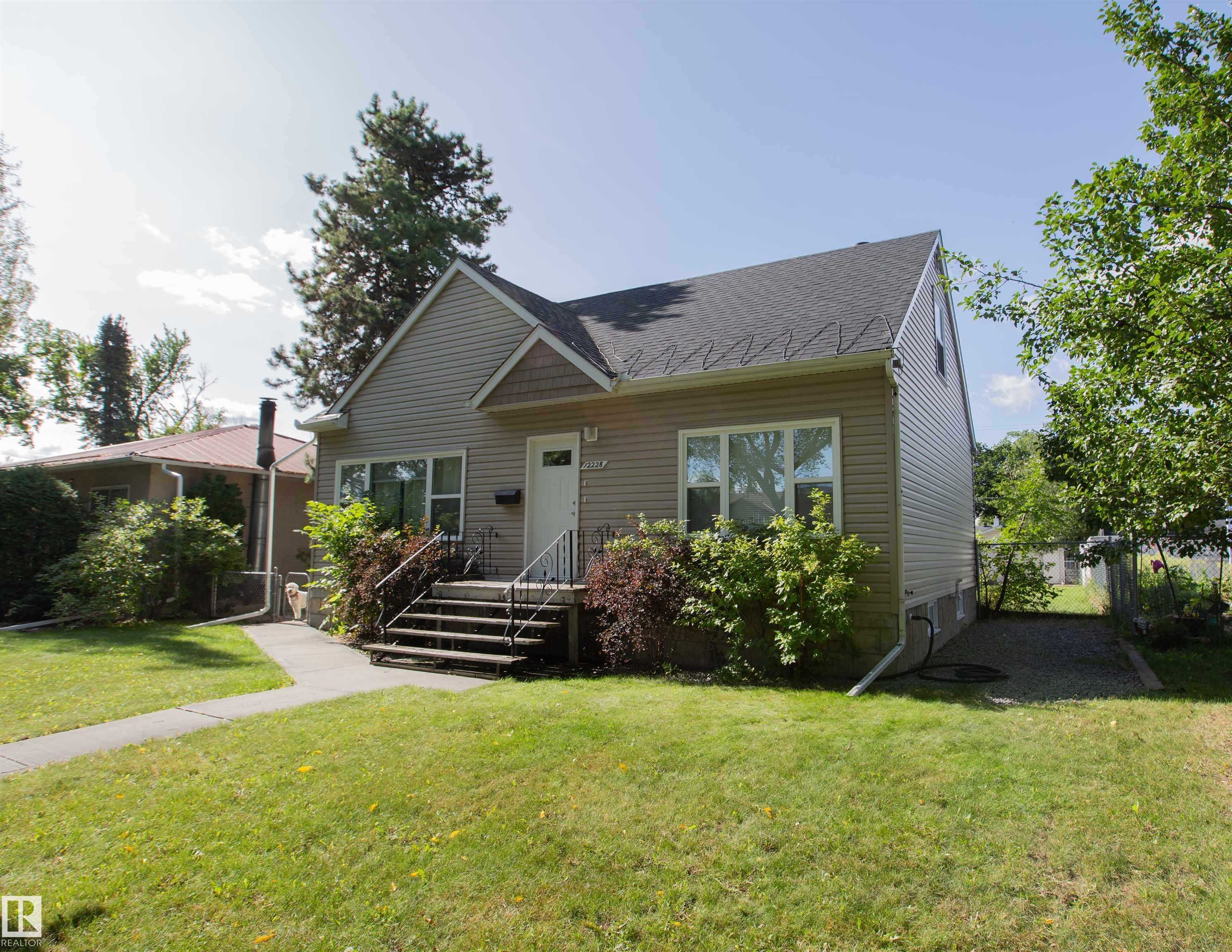 Exterior siding with decorative shingle accents, a dark shingle roof, and a front entry with handrails - 12228 134 Street Nw, Edmonton, AB