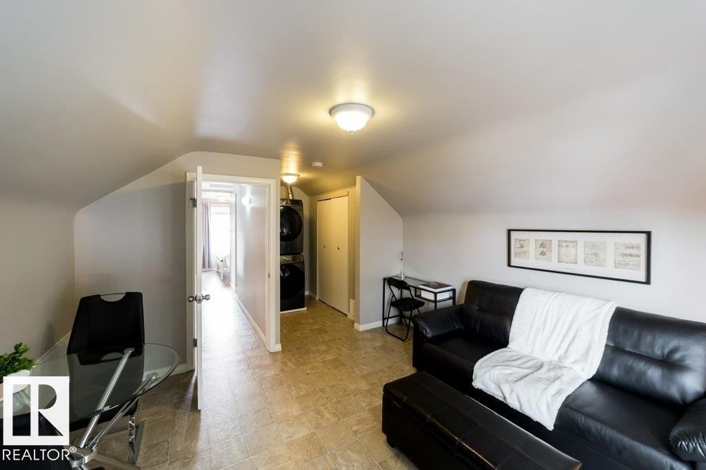 Sloped ceilings with flush mount lighting, durable tile flooring, and a built-in stacked washer and dryer unit - 12228 134 Street Nw, Edmonton, AB