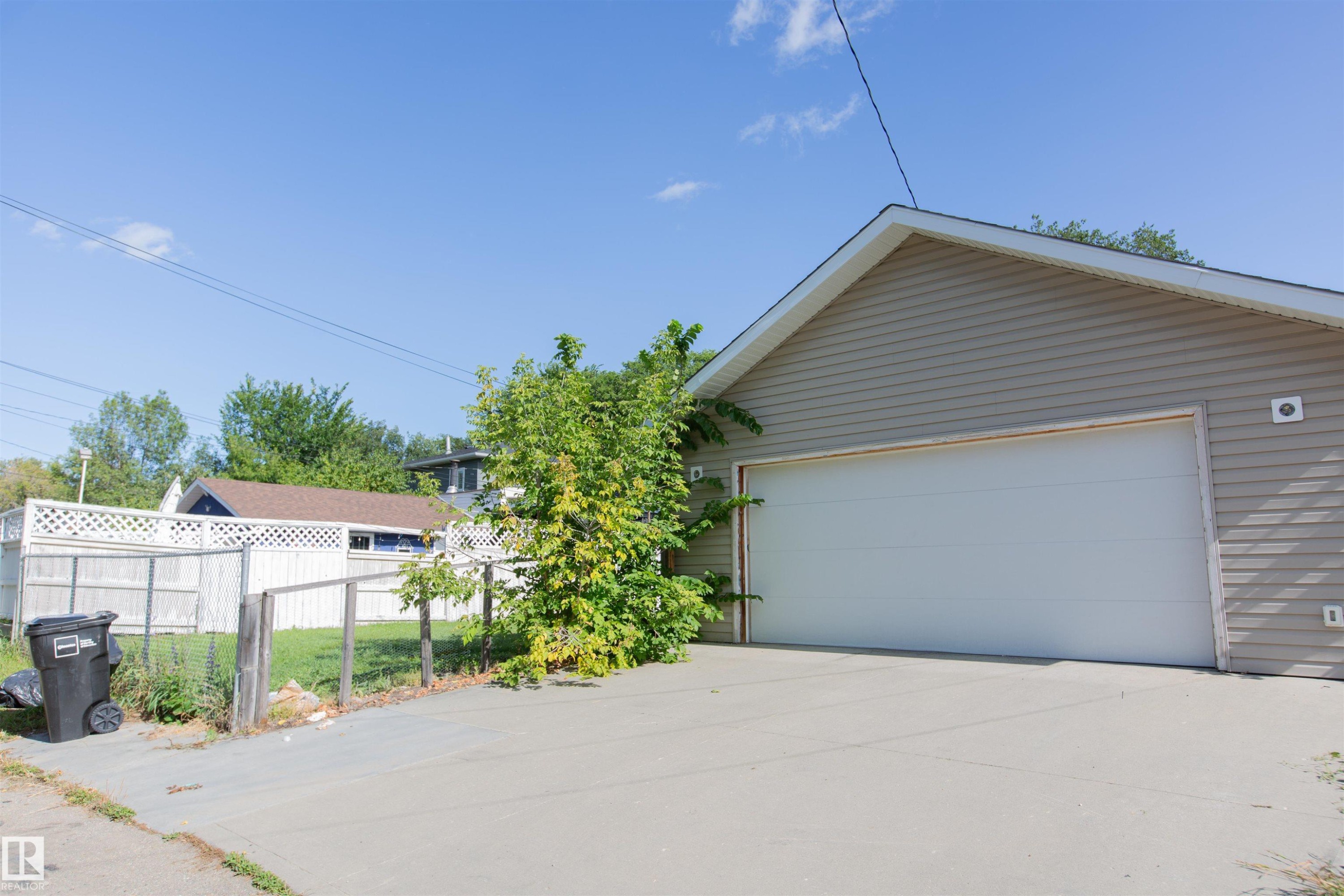 Siding exterior with a large garage door and concrete driveway - 12228 134 Street Nw, Edmonton, AB