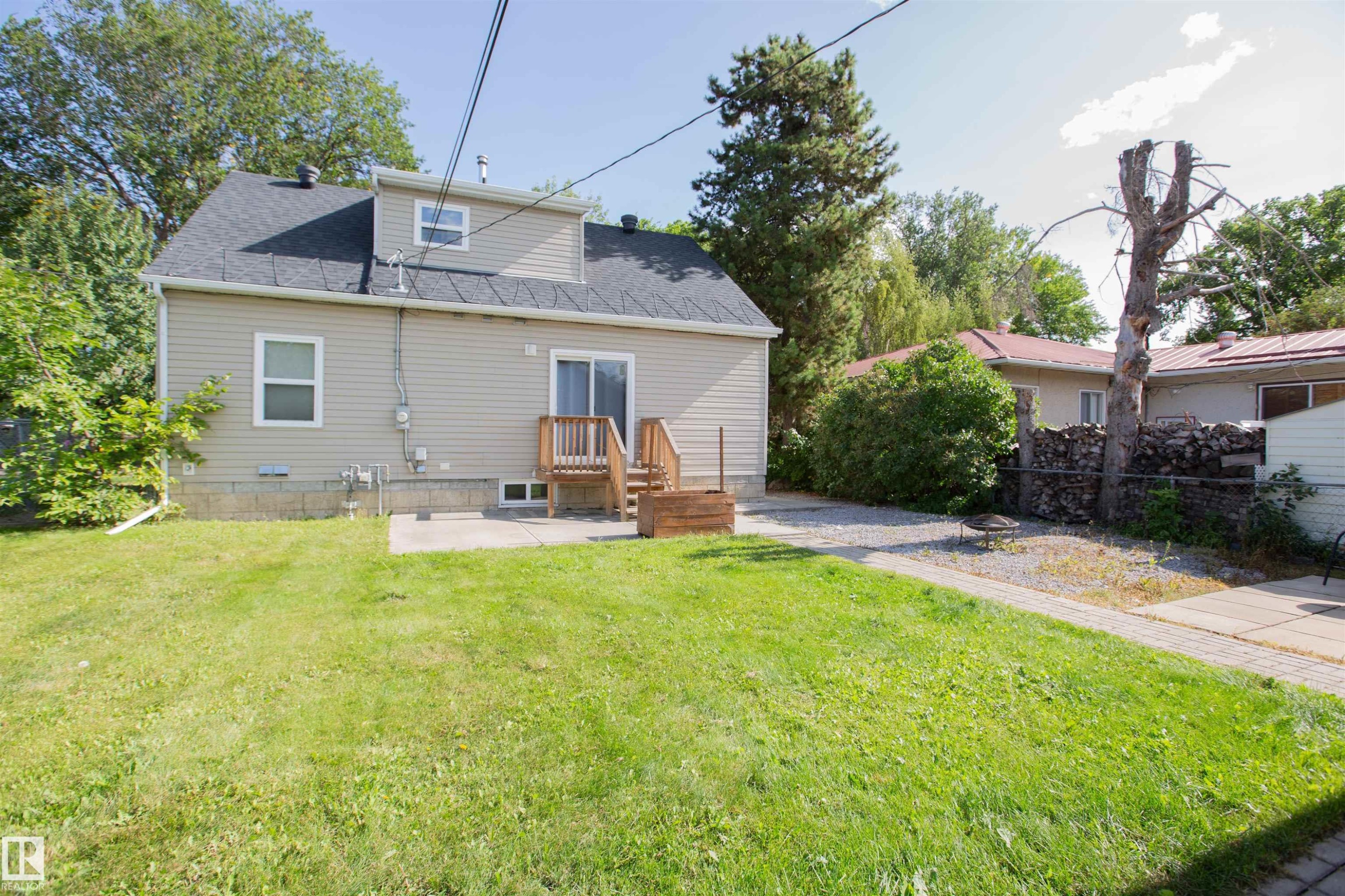 Expansive grassy yard with a concrete patio and gravel pathways - 12228 134 Street Nw, Edmonton, AB