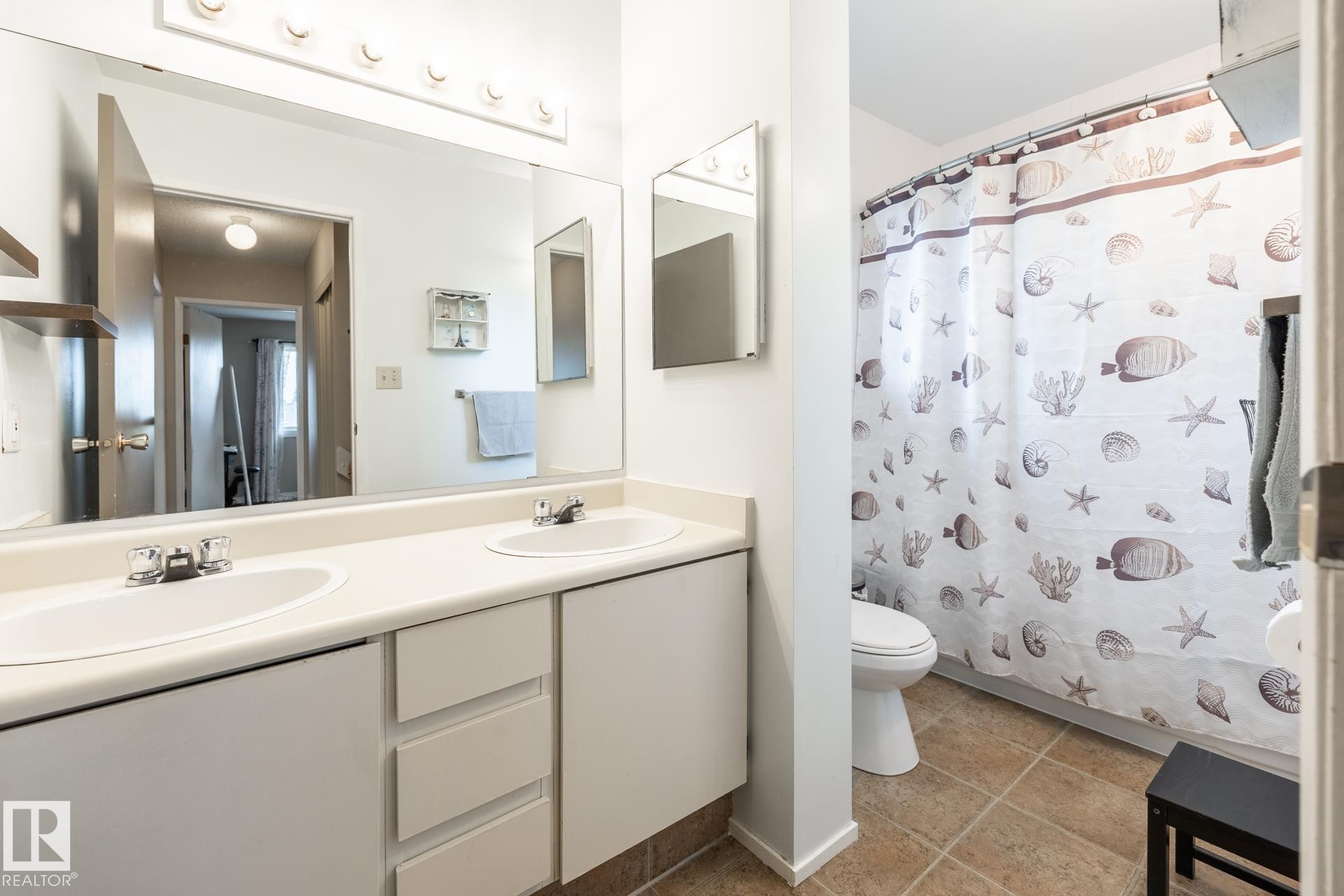 Bathroom featuring a dual-sink vanity with ample counter space, full-width mirror, and a built-in light fixture - #20 3812 20 Av Nw, Edmonton, AB
