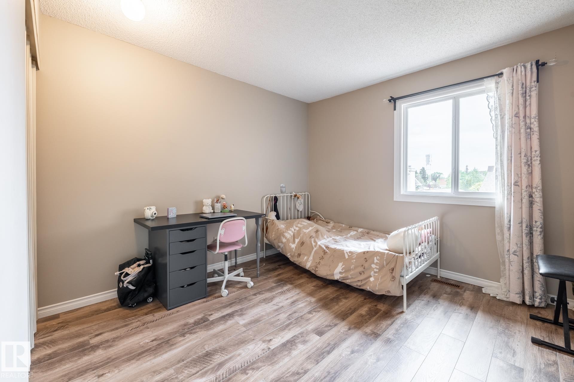 Room featuring wood-finish flooring, neutral wall paint, and a white-framed window with a black curtain rod - #20 3812 20 Av Nw, Edmonton, AB