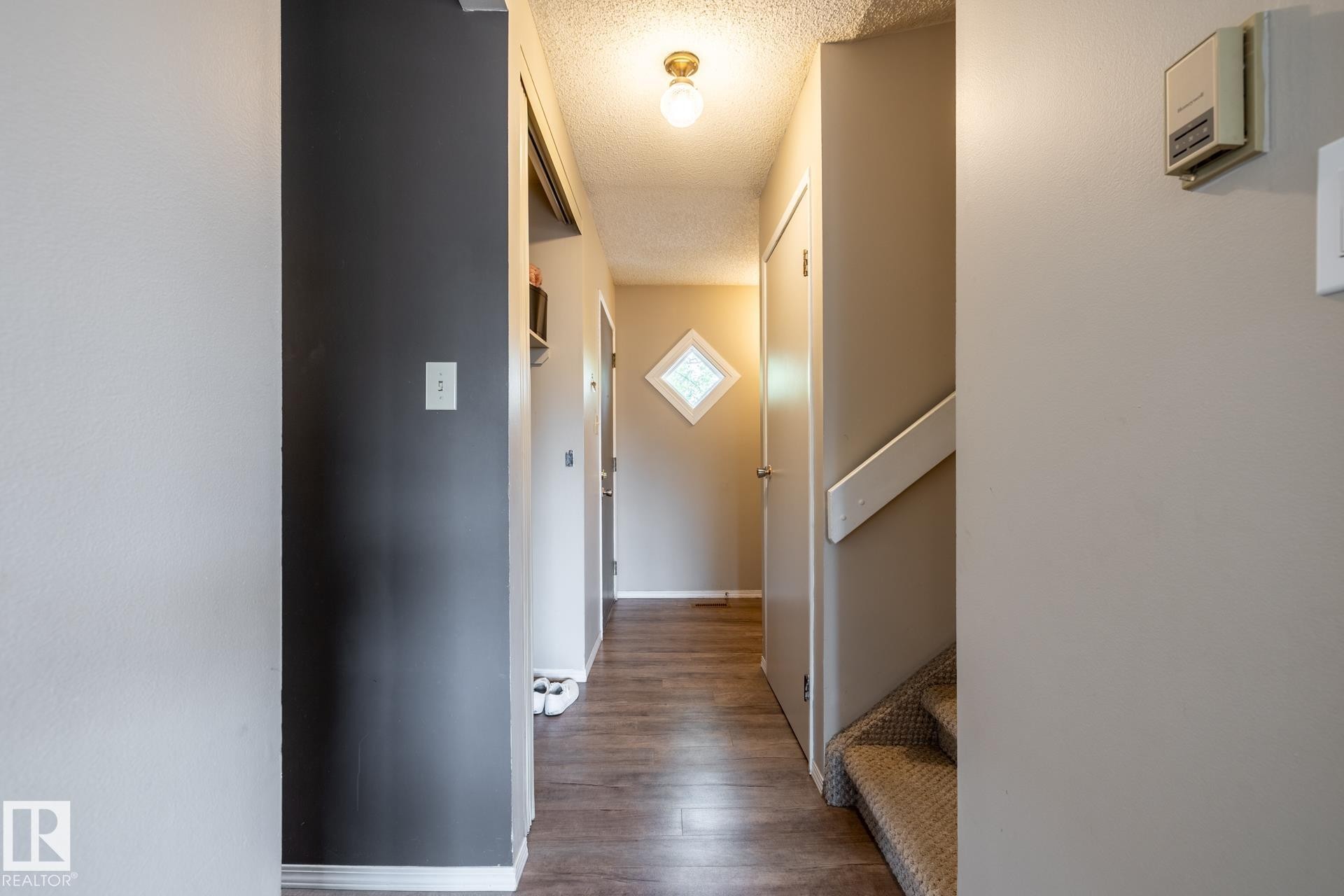 Hallway with wood-finish flooring and a diamond-shaped window - #20 3812 20 Av Nw, Edmonton, AB