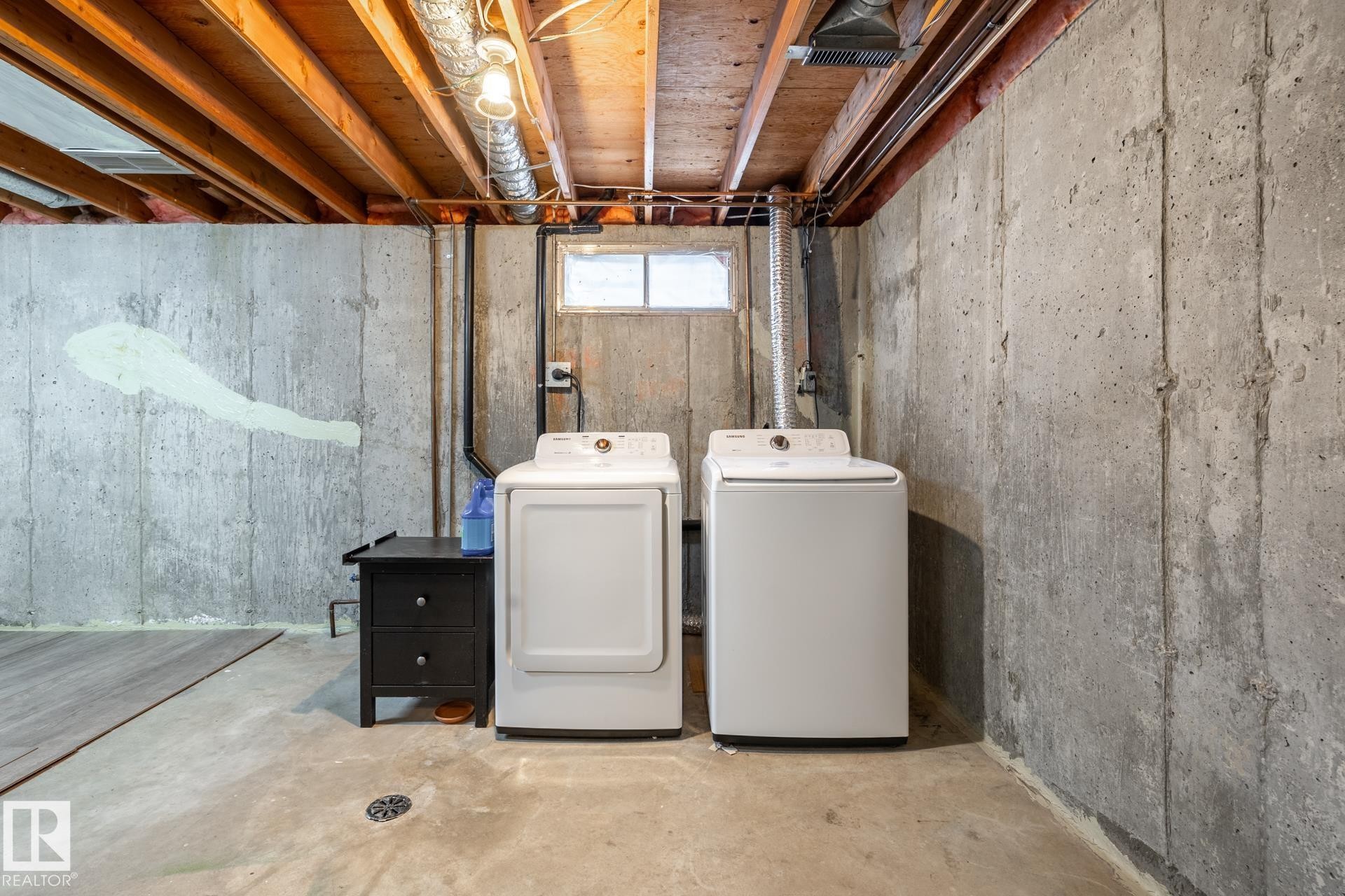 Utility area featuring concrete walls, exposed ceiling joists, and a small casement window - #20 3812 20 Av Nw, Edmonton, AB