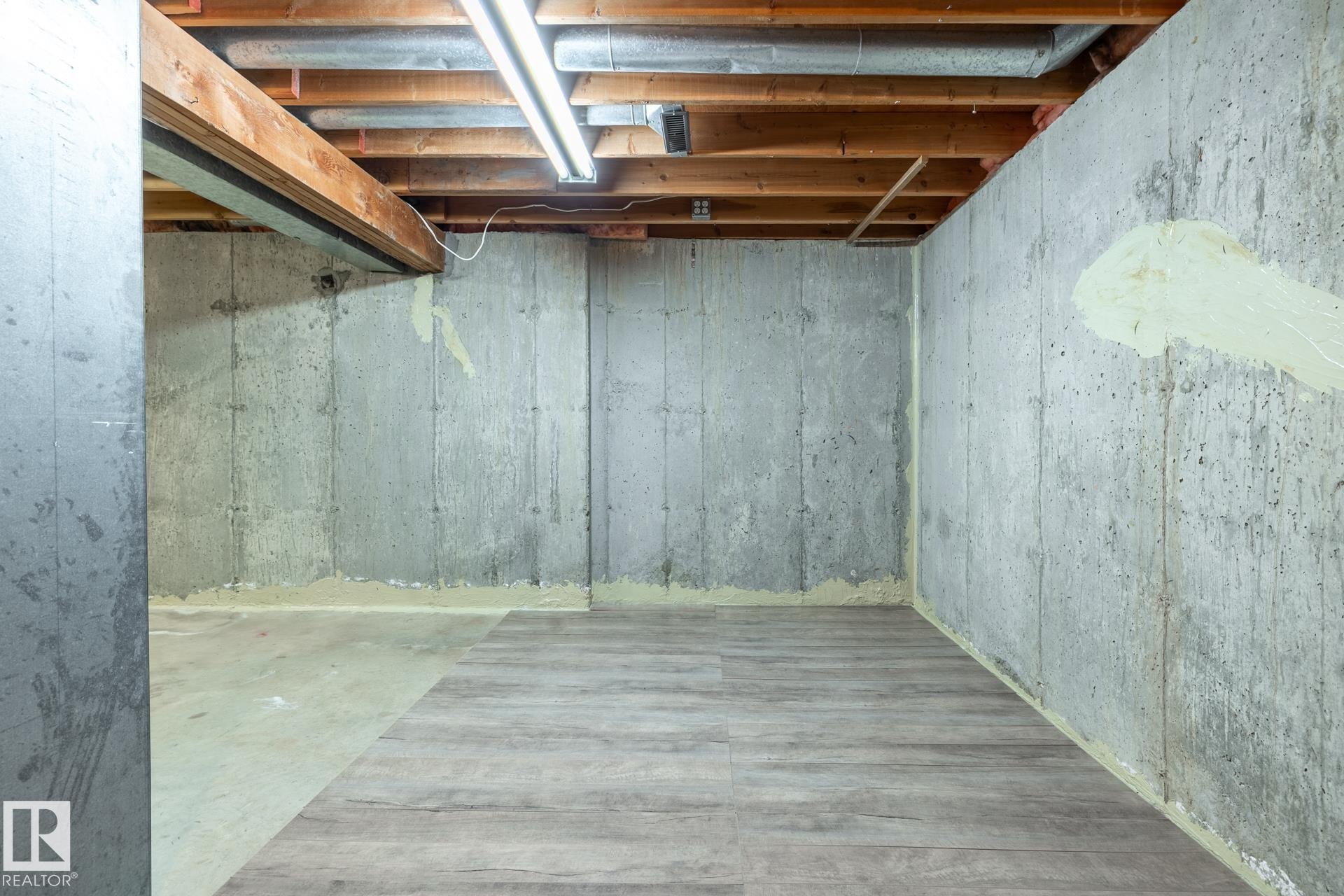 Unfinished basement space featuring exposed concrete walls and ceiling joists - #20 3812 20 Av Nw, Edmonton, AB