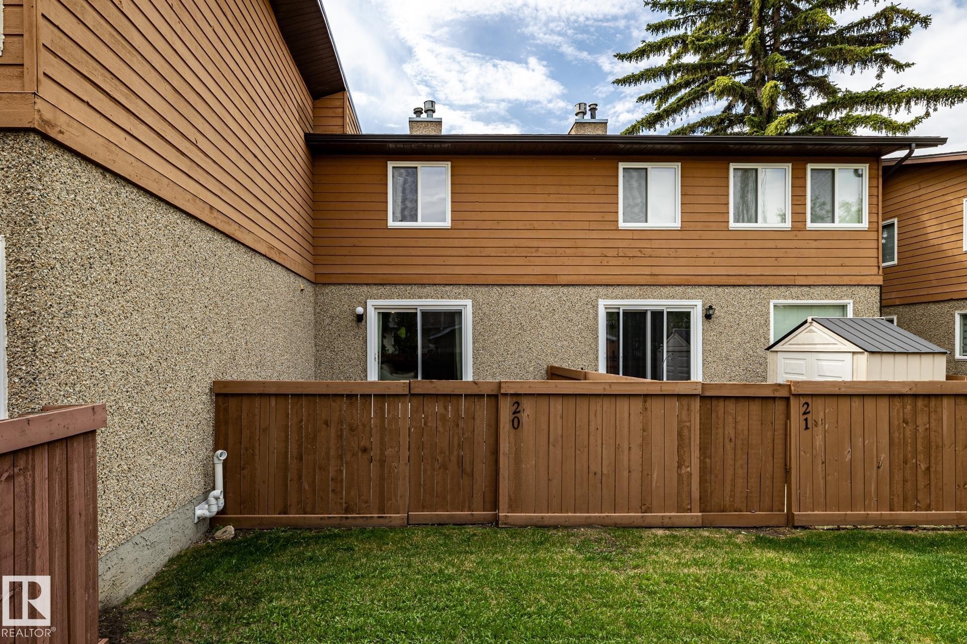 Private fenced yard featuring a manicured lawn, a storage shed, and a privacy fence - #20 3812 20 Av Nw, Edmonton, AB