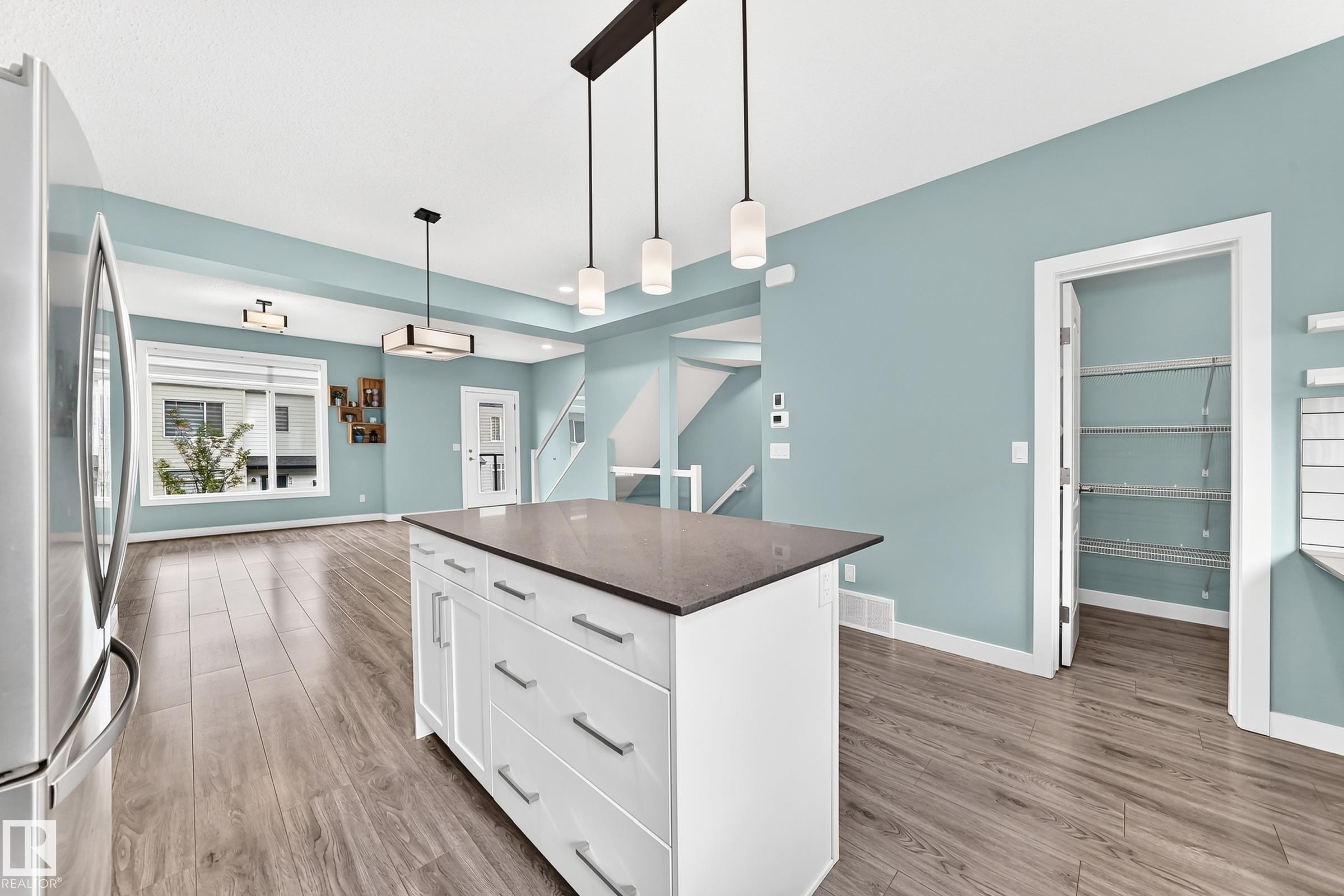 Central kitchen island with a dark countertop and white cabinetry - #56 804 Welsh Dr Sw, Edmonton, AB
