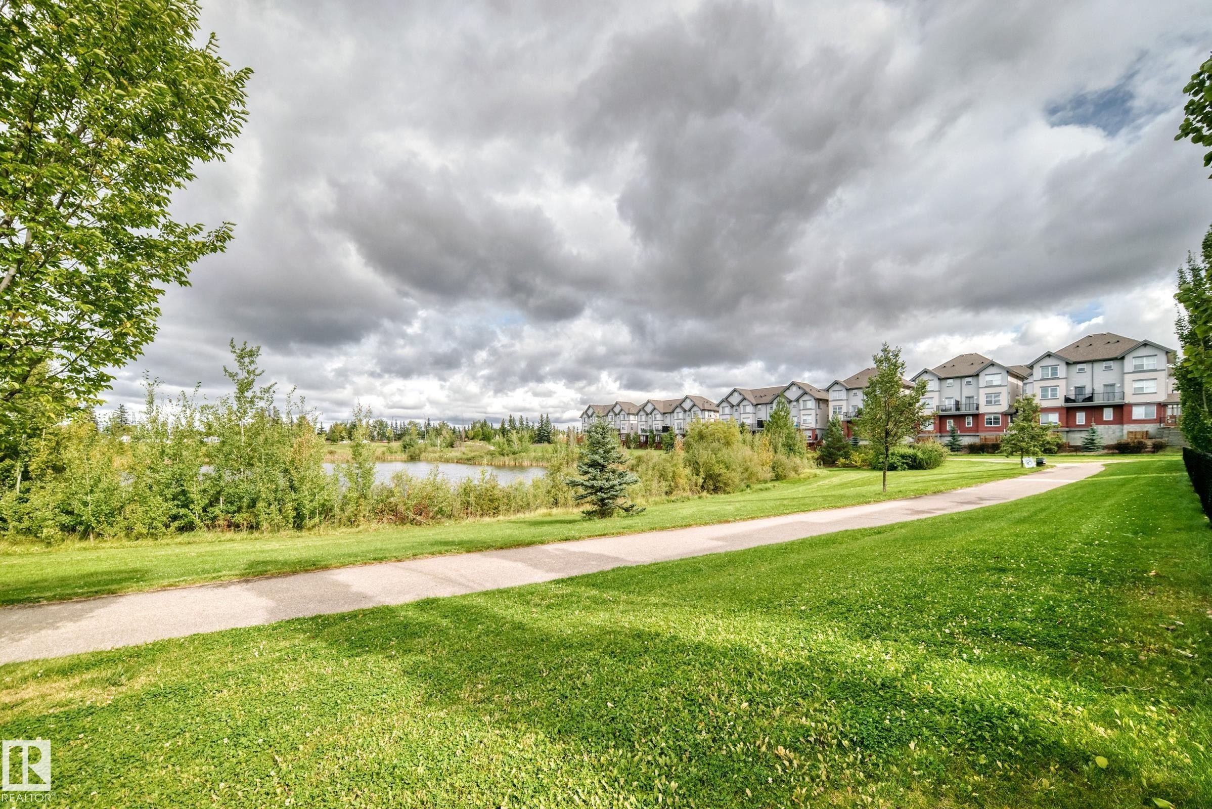 Paved pathway bordering a body of water with multi-story residential structures - #56 804 Welsh Dr Sw, Edmonton, AB