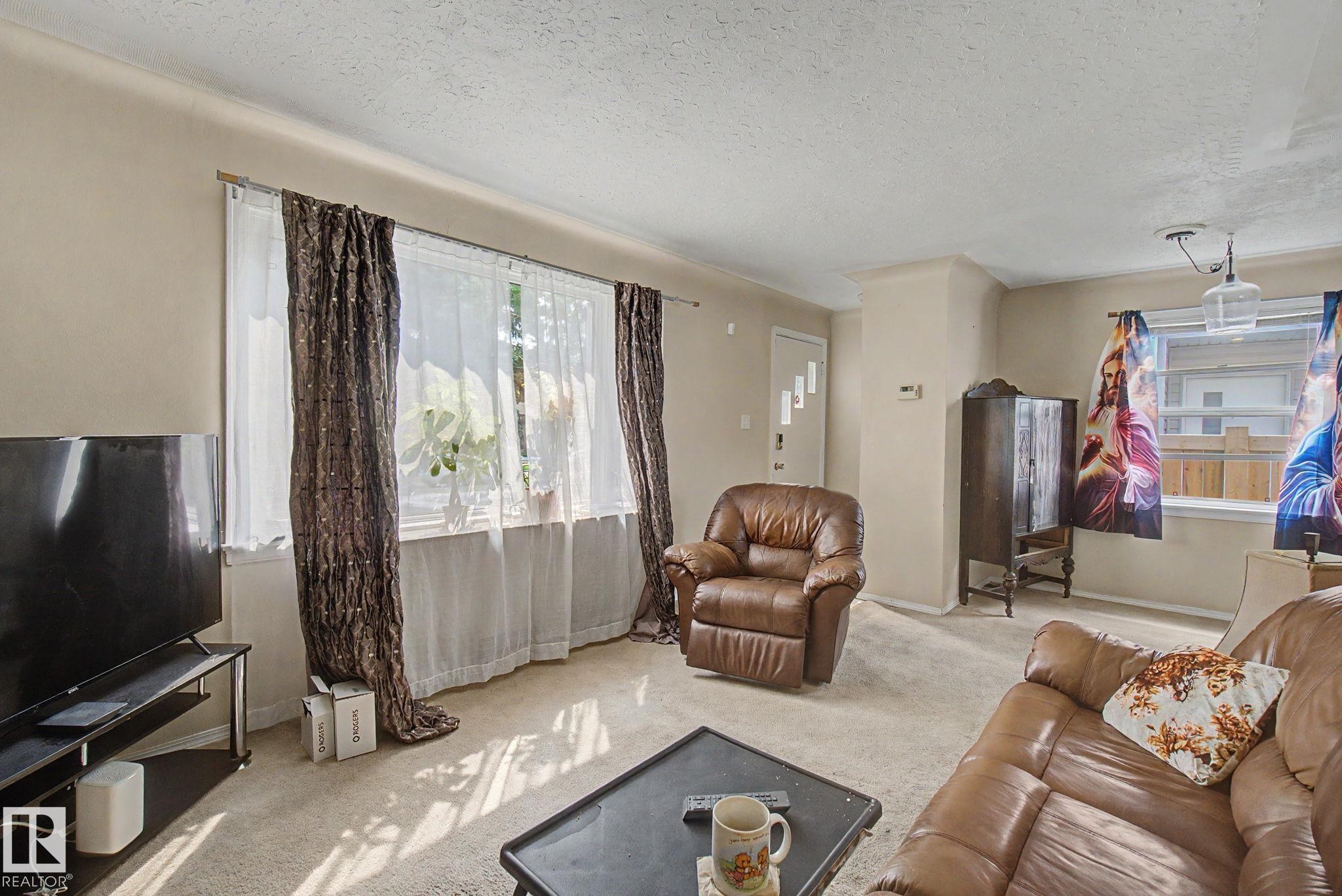Light-toned walls complement the neutral carpet flooring - 8710 83 Avenue Nw, Edmonton, AB - Indoor Photo Showing Living Room