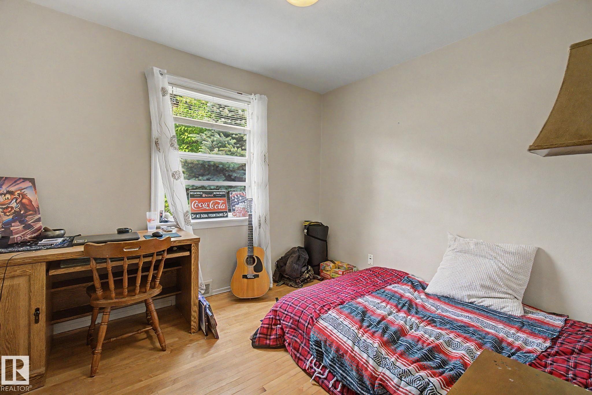 Room featuring wood-finish flooring, a window with exterior tree views, and light-toned wall finishes - 8710 83 Avenue Nw, Edmonton, AB - Indoor Photo Showing Bedroom