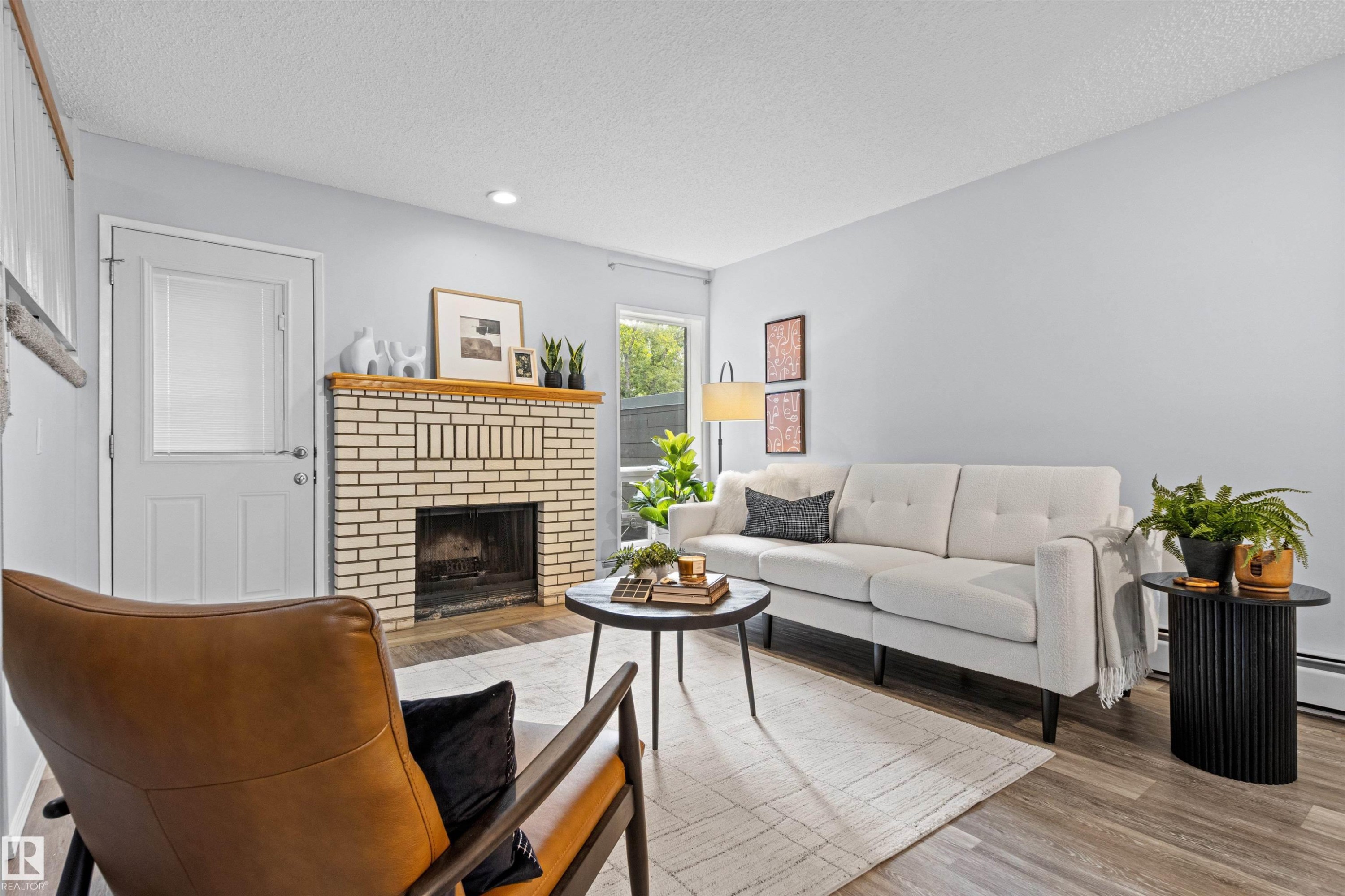Brick fireplace with wood mantel, wood-finish flooring, white paneled door, and recessed lighting - #7 10032 113 St Nw, Edmonton, AB