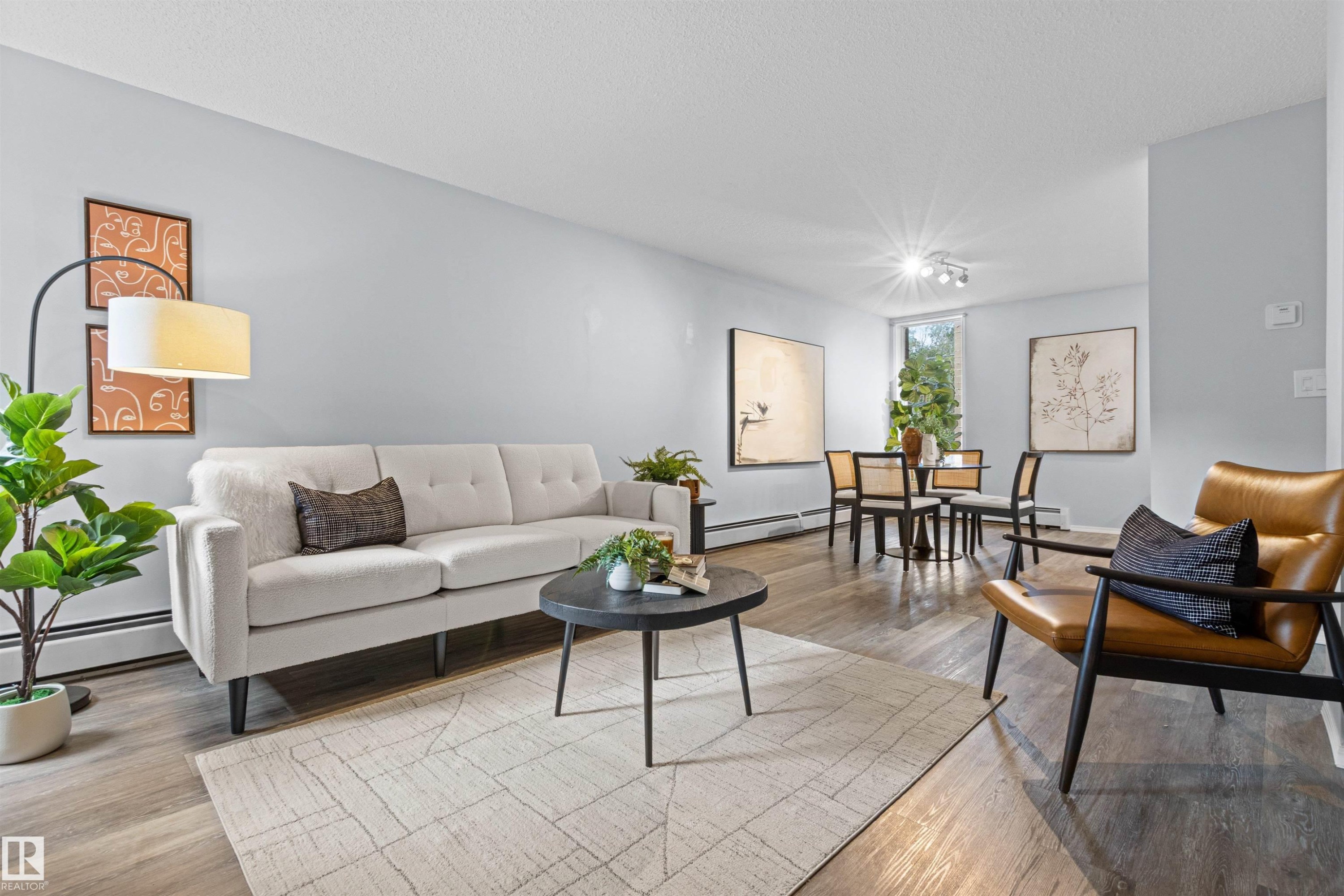 Open-concept living area with wood-finish flooring, light gray wall paint, and a window providing natural light - #7 10032 113 St Nw, Edmonton, AB