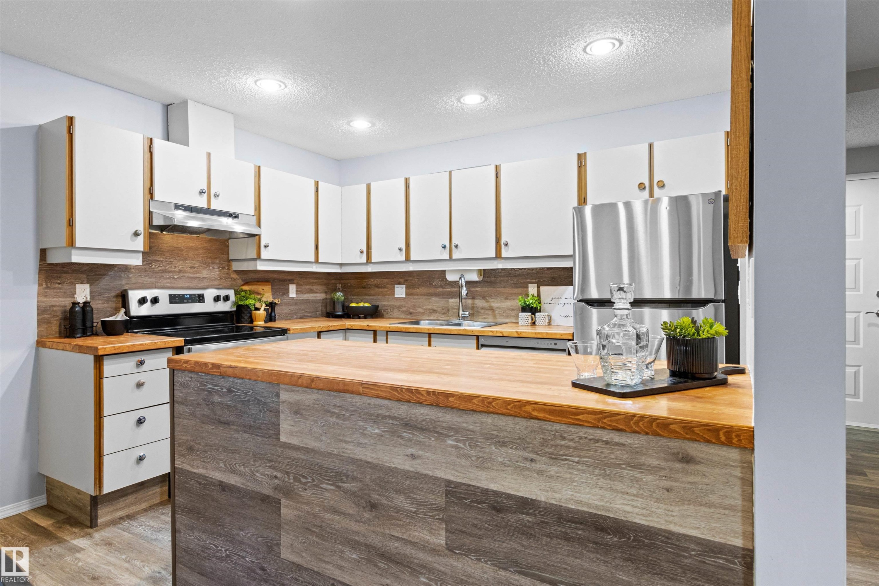 Kitchen featuring white cabinetry, wood-finish countertops, wood-finish backsplash, stainless steel appliances, and recessed lighting - #7 10032 113 St Nw, Edmonton, AB