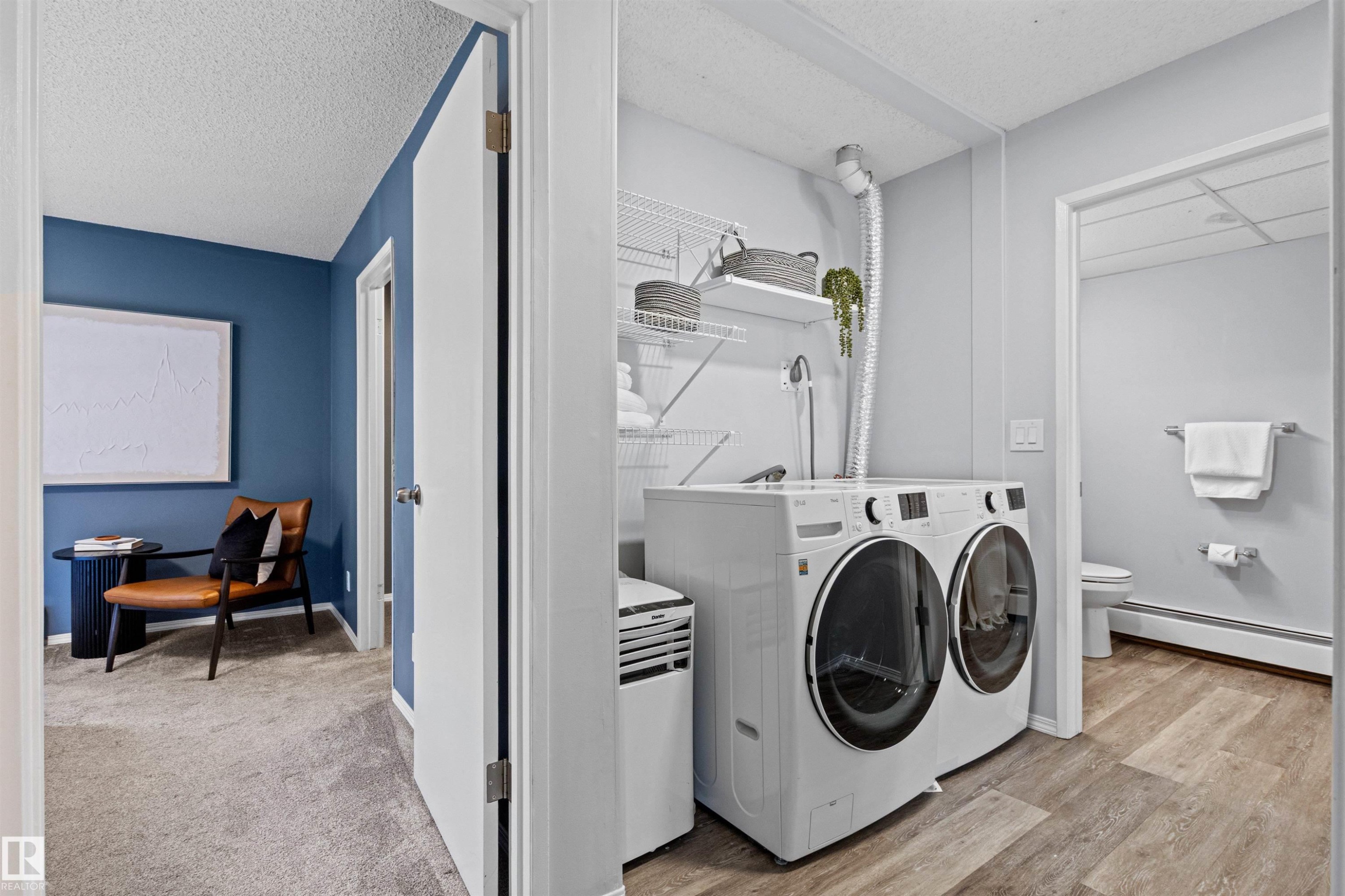 Dedicated laundry area with built-in shelving, wood-finish flooring, and light wall tones - #7 10032 113 St Nw, Edmonton, AB