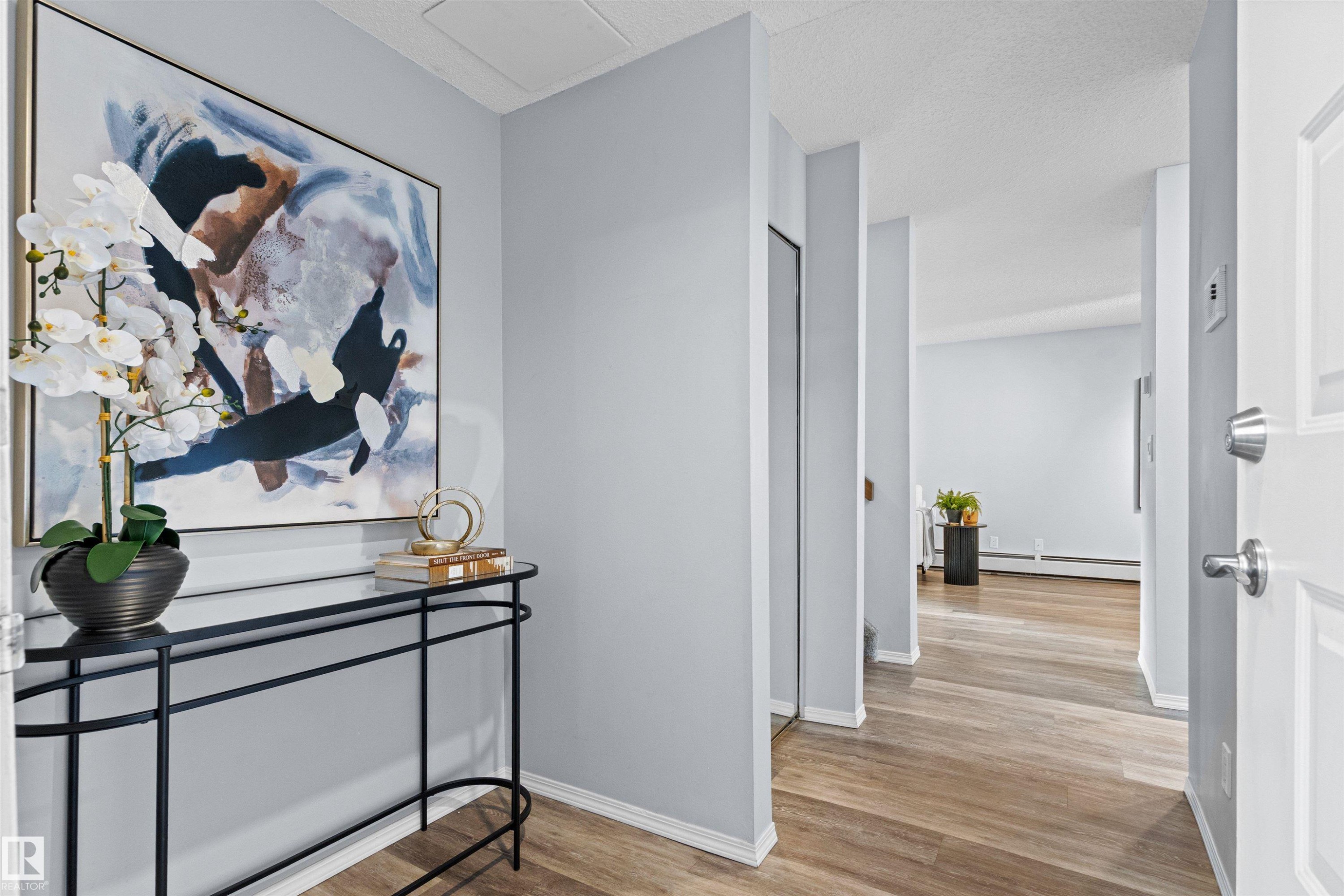 Wood-finish flooring, light grey wall paint, and white trim throughout the interior - #7 10032 113 St Nw, Edmonton, AB