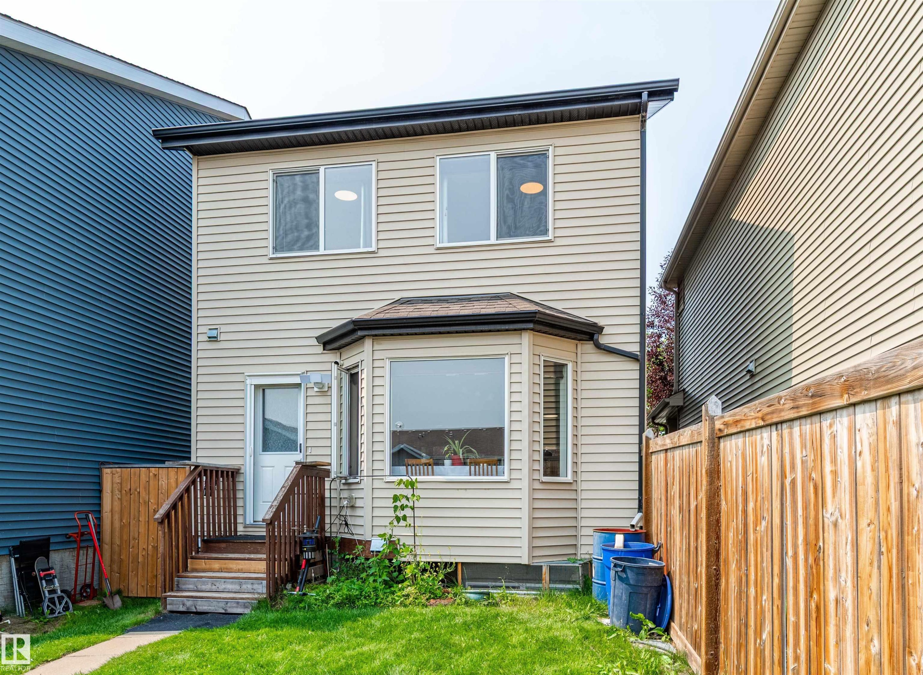 Rear exterior featuring light-colored horizontal siding and a dark shingle roof - 8527 Ellis Link Nw, Edmonton, AB - Outdoor With Exterior