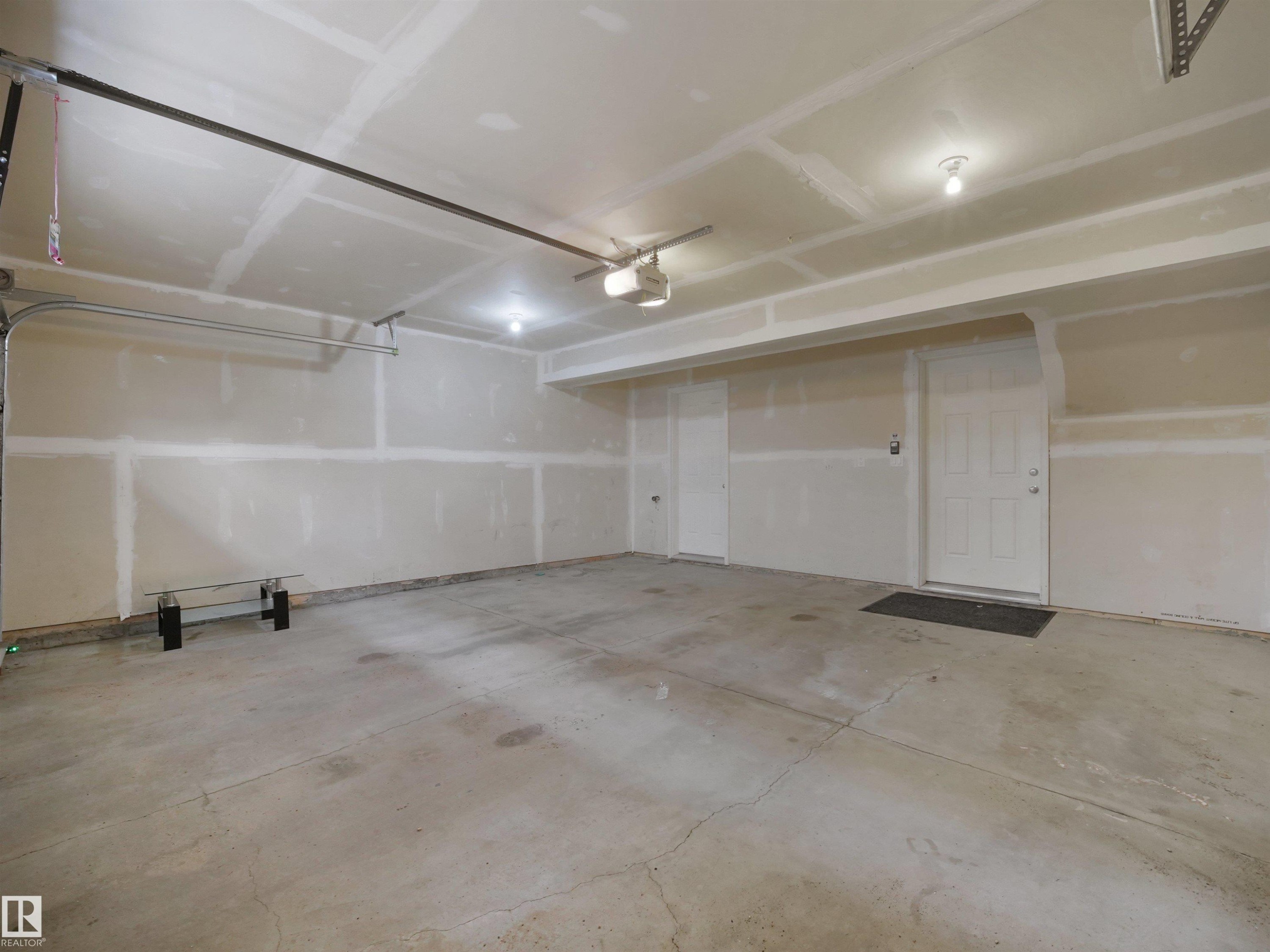 Spacious garage featuring a concrete floor, overhead lighting, and two entry doors - #40 2003 Rabbit Hill Rd Nw, Edmonton, AB
