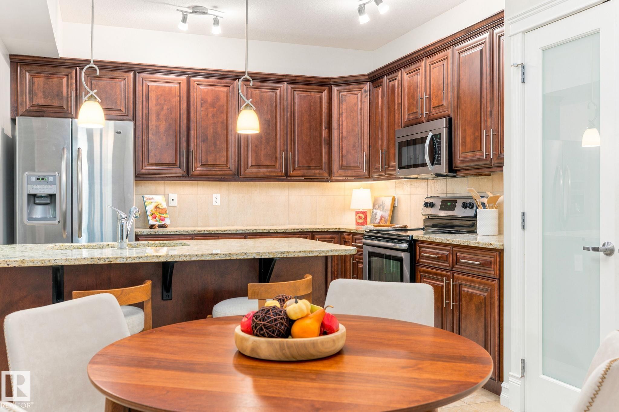 Kitchen featuring rich wood cabinetry, stainless steel appliances, light-toned countertops, and track lighting - 10143 123 Street Nw, Edmonton, AB