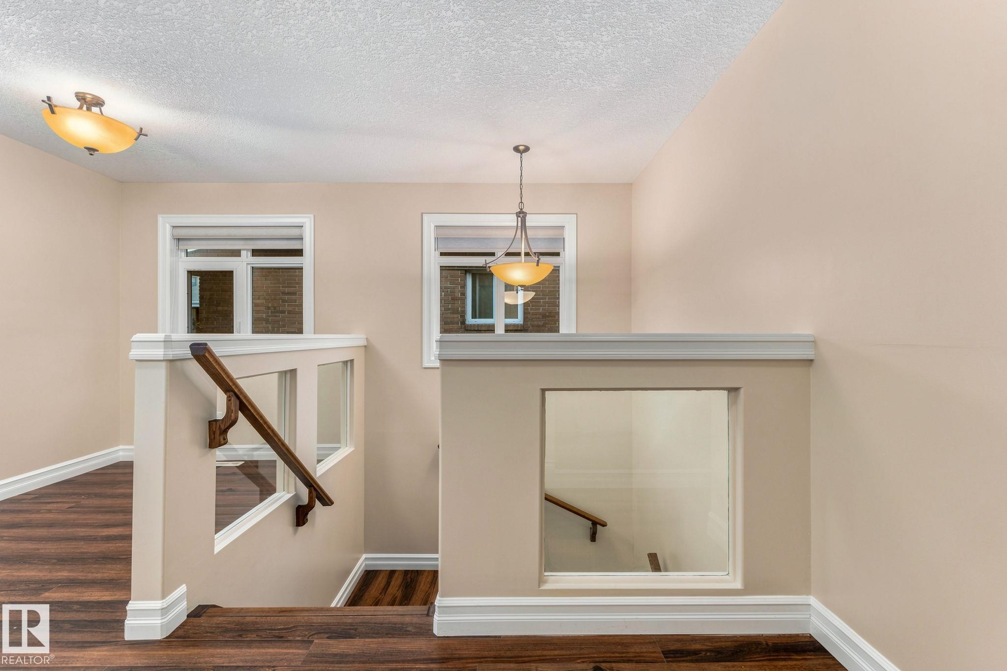 Wood-finish flooring, white trim, recessed windows, glass panel railing, and pendant lighting - 10143 123 Street Nw, Edmonton, AB