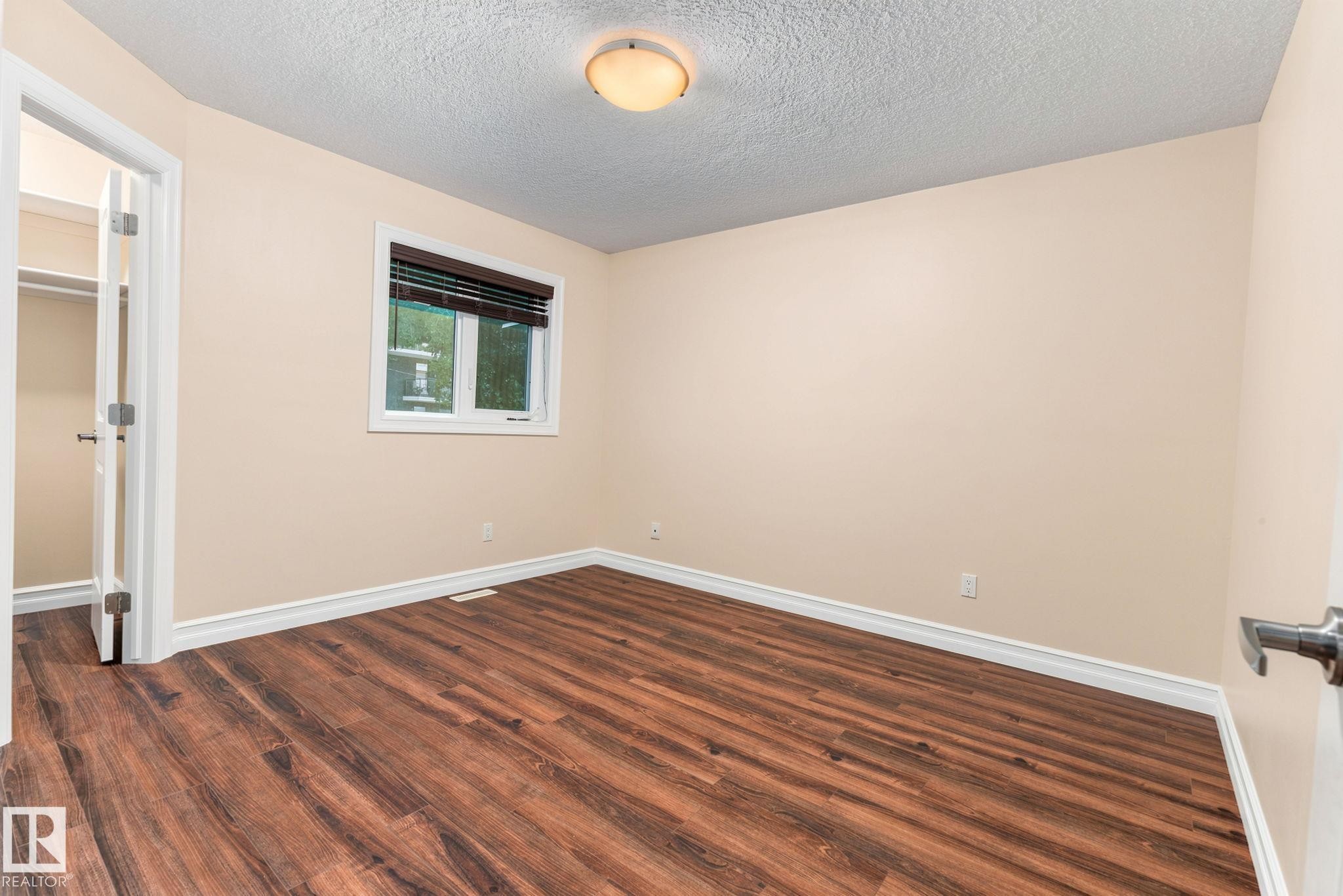 Wood-finish flooring, neutral wall tones, window with horizontal blinds, built-in closet, and a ceiling-mounted light fixture - 10143 123 Street Nw, Edmonton, AB