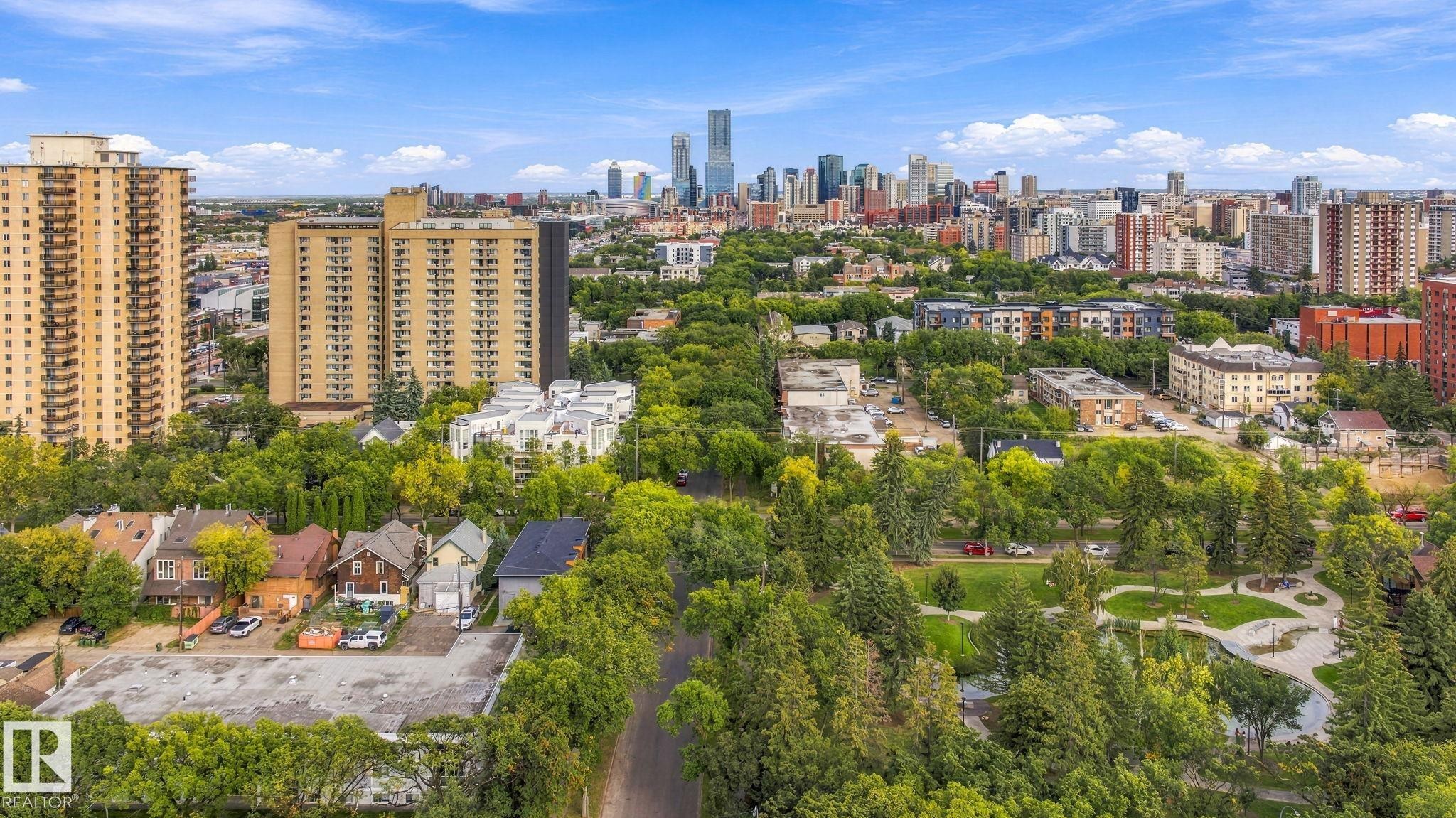 Lush tree-lined streetscape with a city skyline backdrop, featuring a mix of residential buildings and green spaces - 10143 123 Street Nw, Edmonton, AB