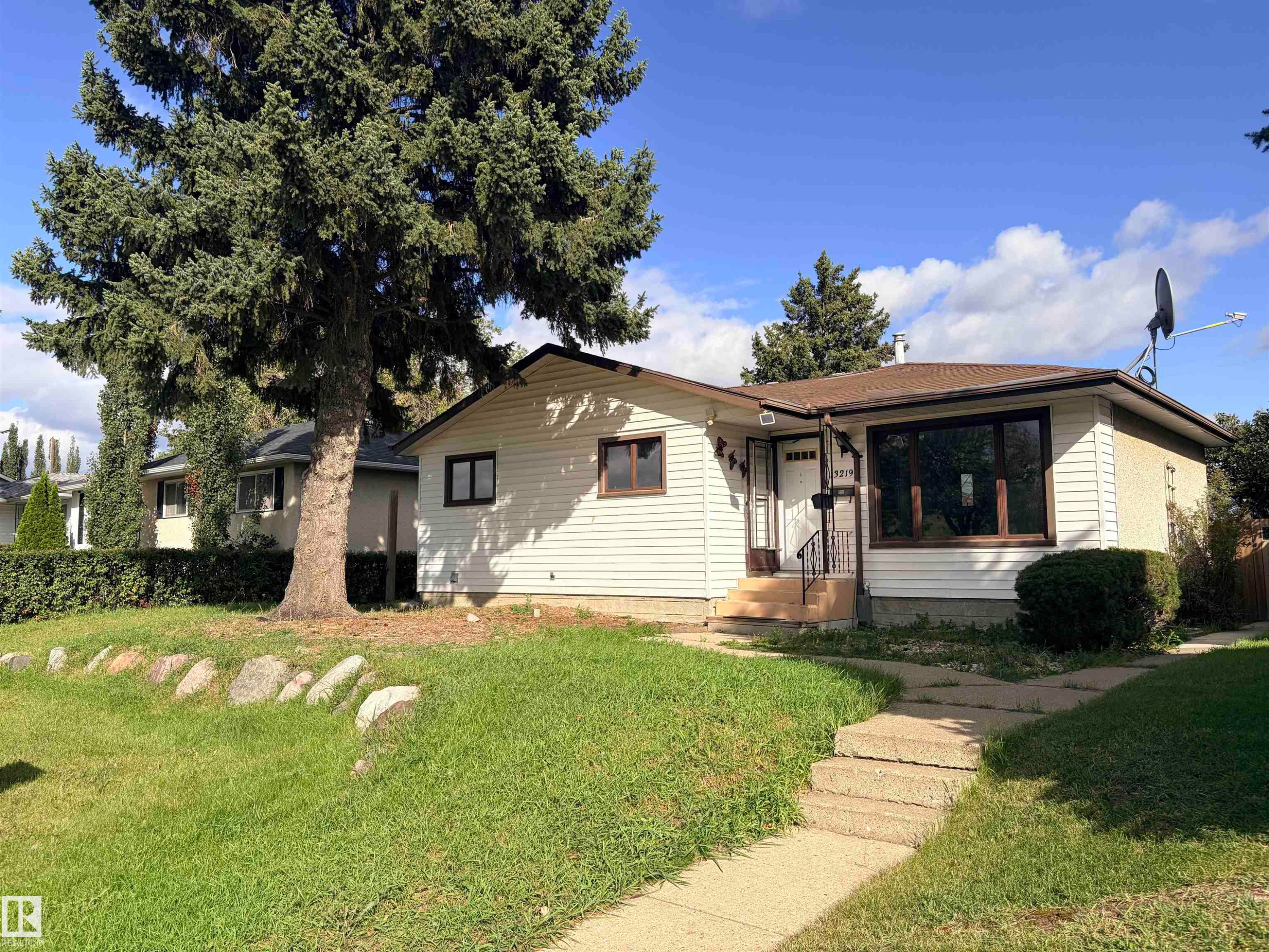 Front exterior with horizontal siding, a large picture window, and a concrete pathway - 13219 107 Street Nw, Edmonton, AB