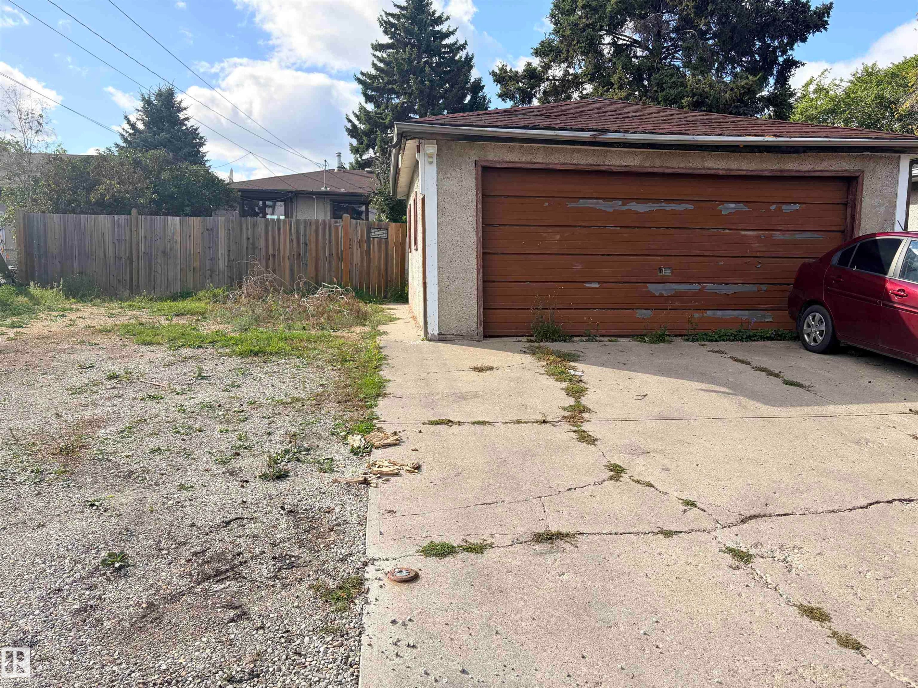 Detached garage with a wood-finish overhead door, stucco exterior, and asphalt shingle roof - 13219 107 Street Nw, Edmonton, AB