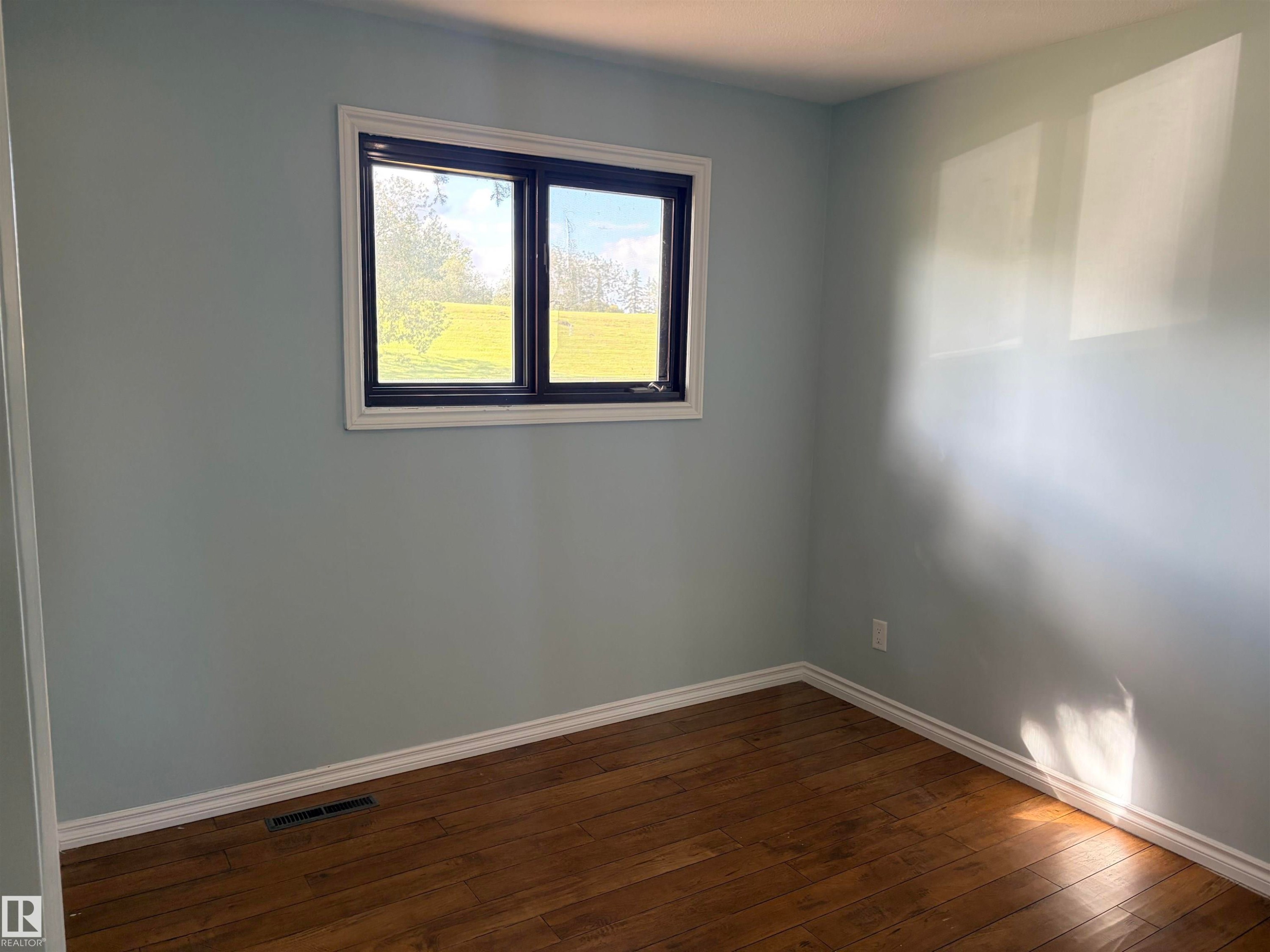 Wood-finish flooring with white trim and a window featuring dark framing Bedrooms 2 - 13219 107 Street Nw, Edmonton, AB