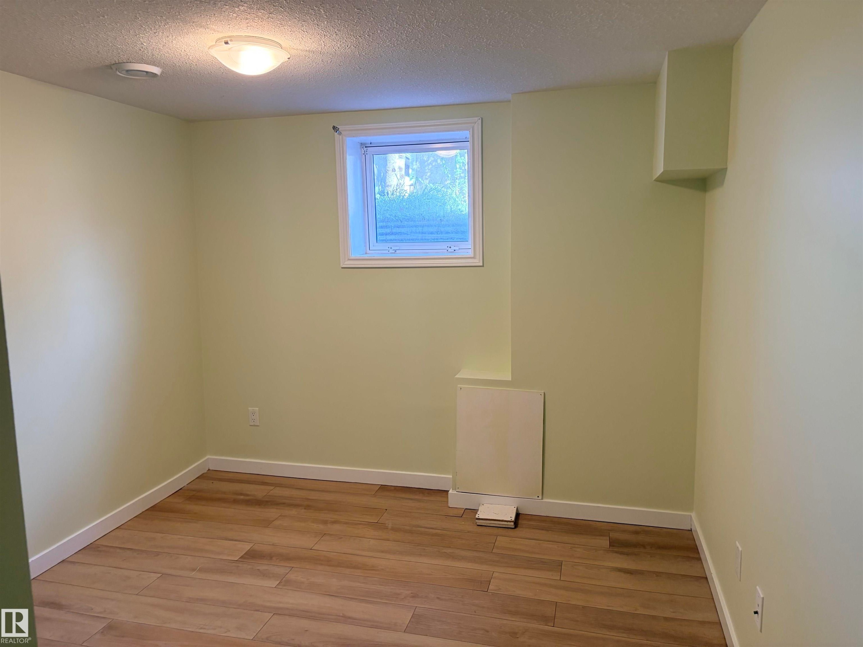 Recessed window, wood-finish flooring, flush mount ceiling light, light-toned wall paint, white trim basement bedroom - 13219 107 Street Nw, Edmonton, AB