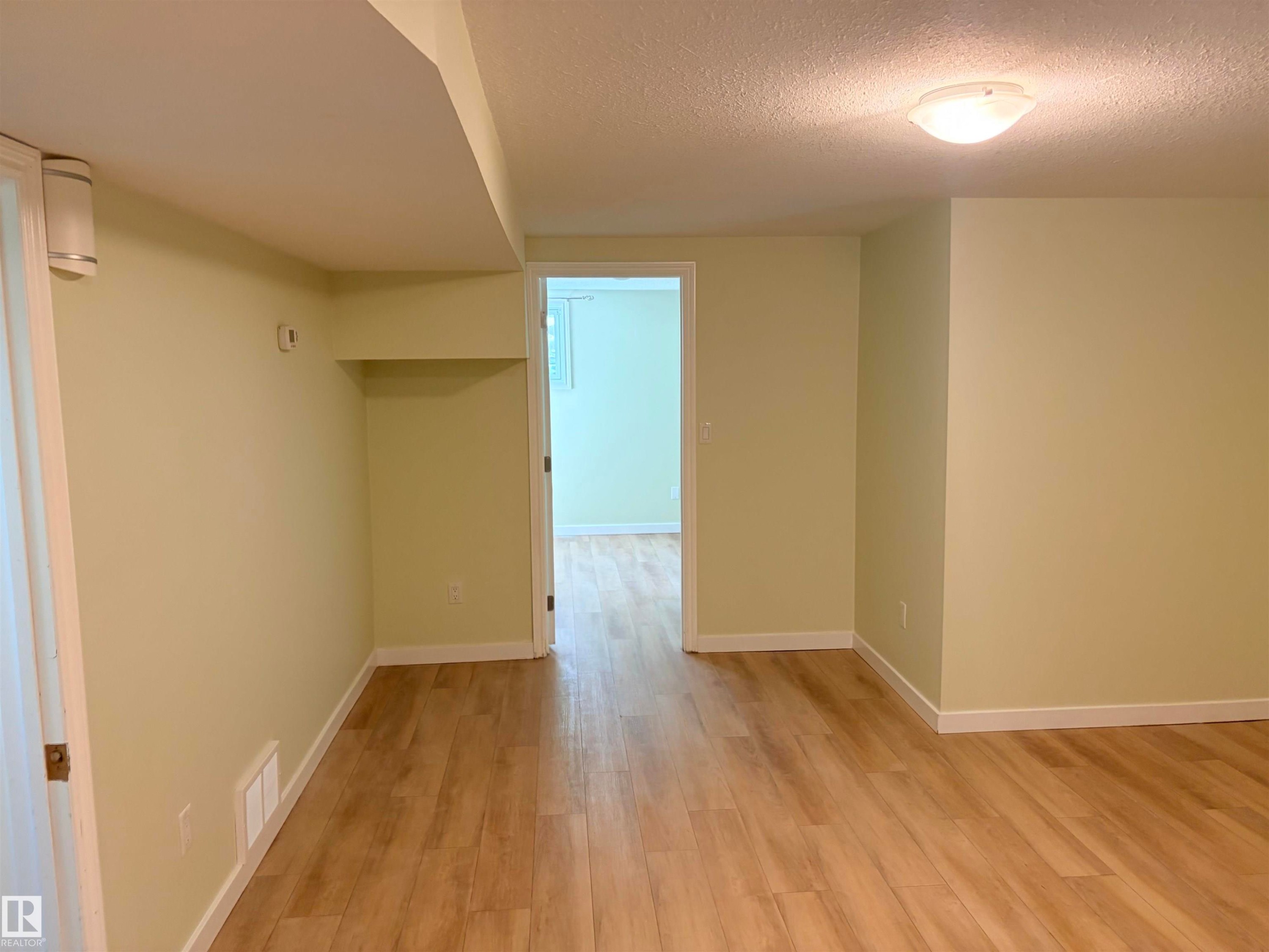 Wood-finish flooring throughout, light-toned walls, and a semi-flush mount ceiling light - 13219 107 Street Nw, Edmonton, AB