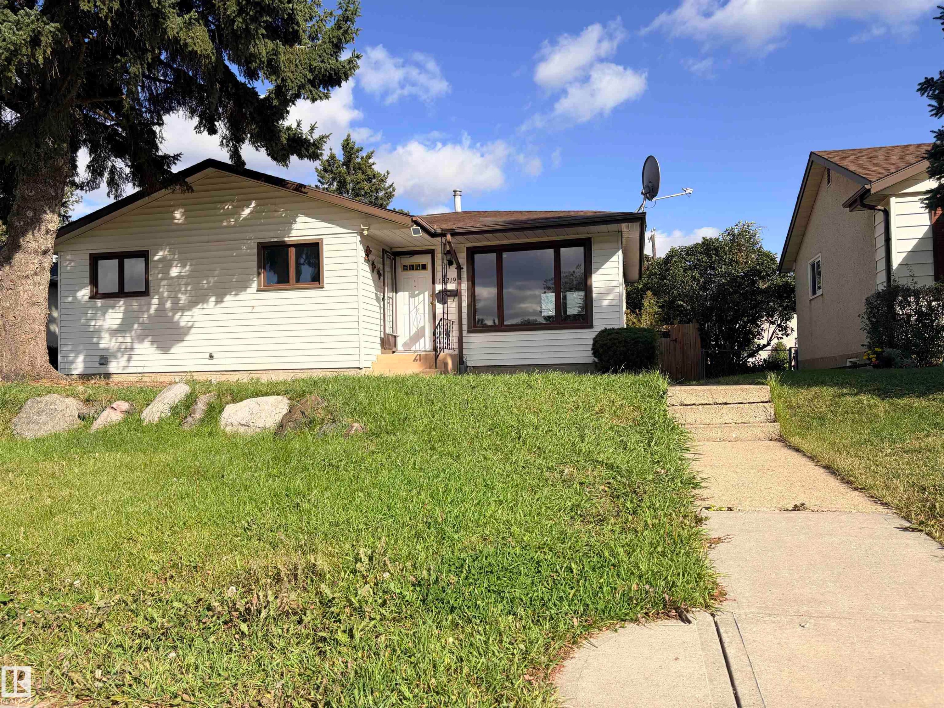 White siding exterior with a brown shingle roof, dark-framed windows, and an established front yard - 13219 107 Street Nw, Edmonton, AB