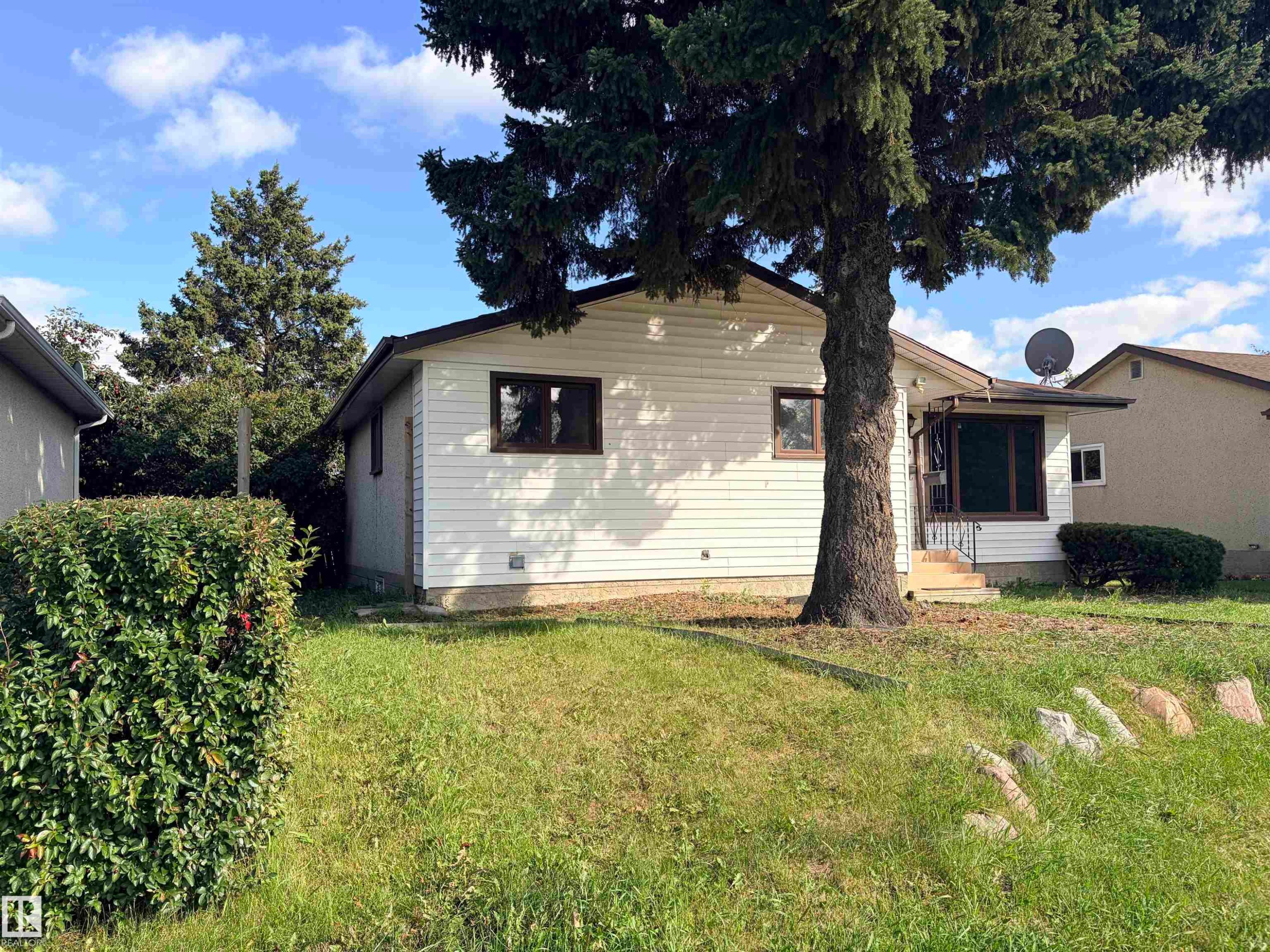White siding exterior with dark-framed windows, a covered entrance, and mature trees - 13219 107 Street Nw, Edmonton, AB